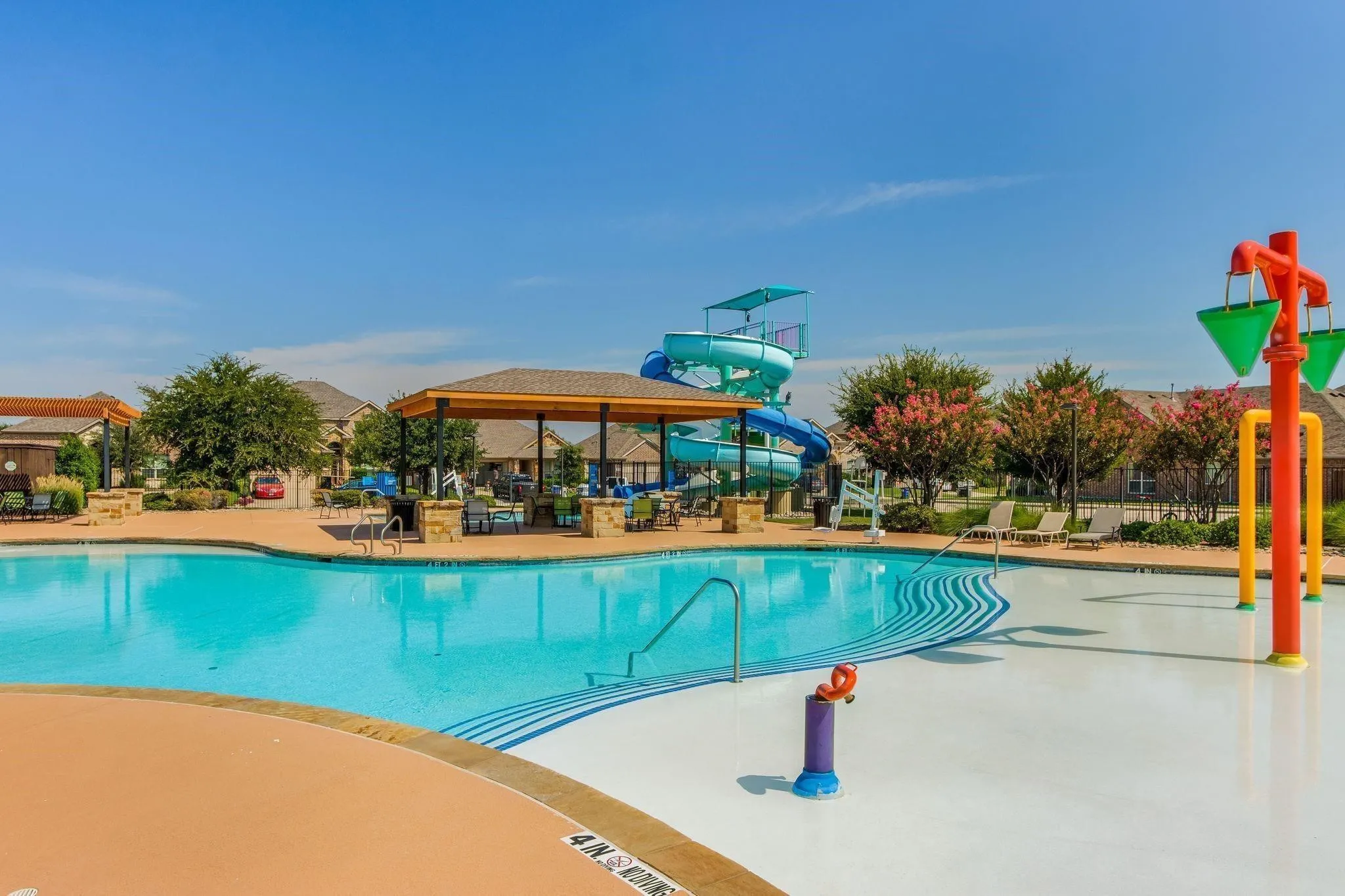 Community pool featuring a water slide, splash pad, and shaded cabanas
