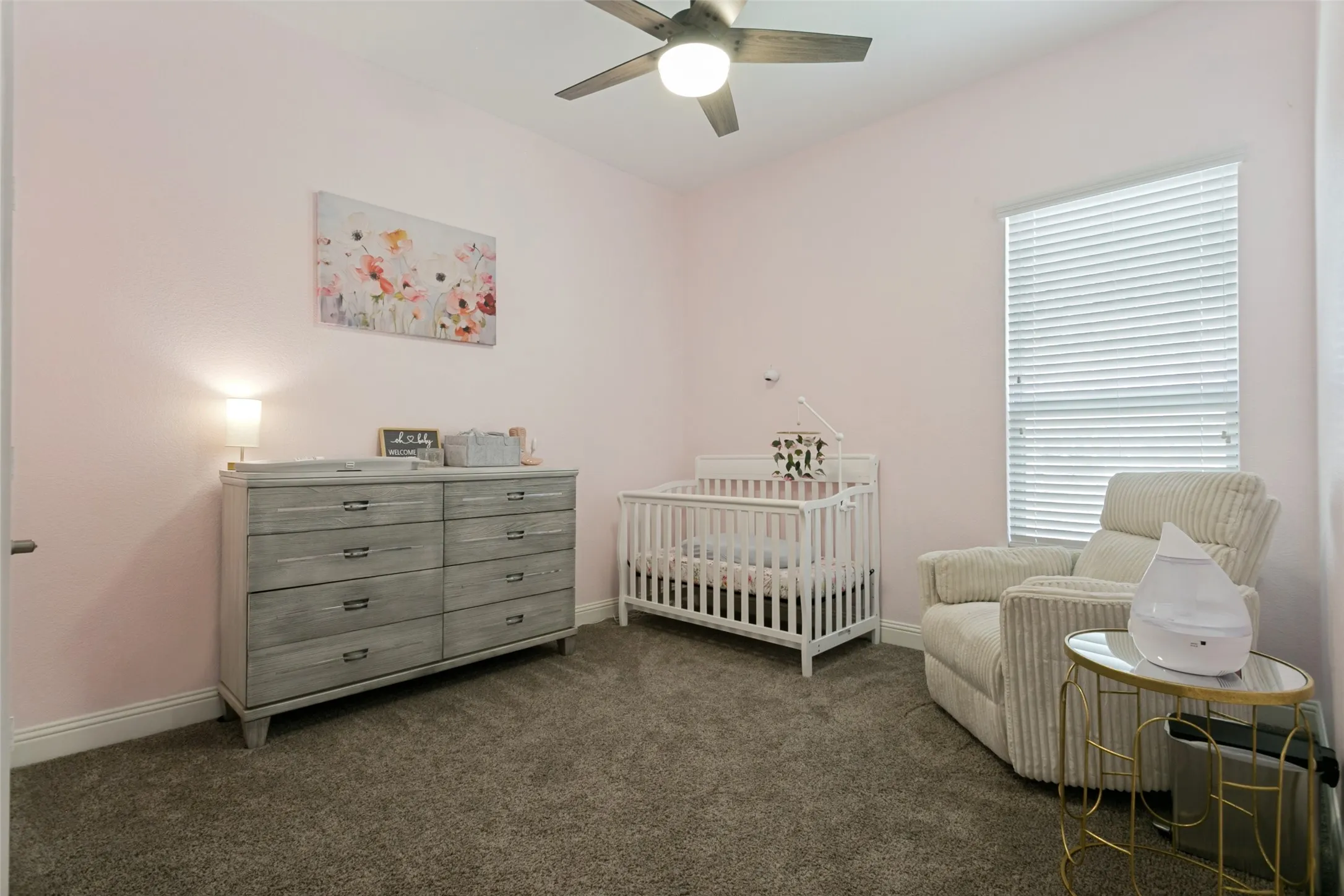 Carpeted room featuring a ceiling fan with integrated lighting, a window with horizontal blinds, and baseboard molding