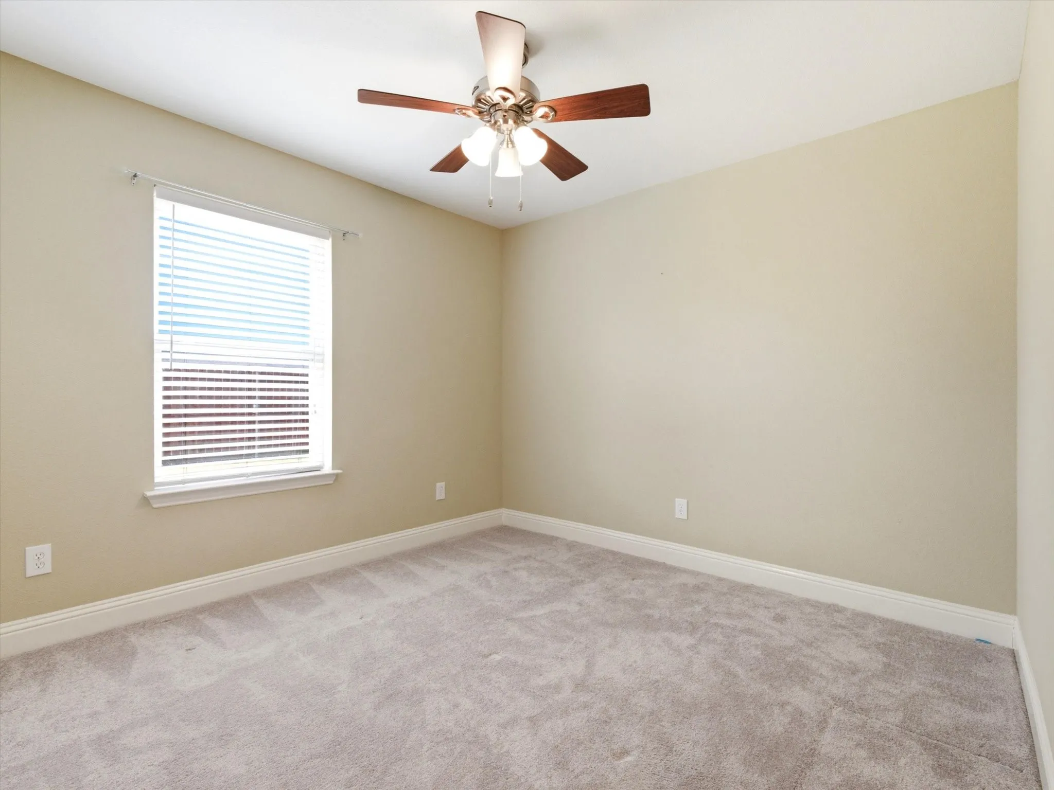 Spacious bedroom offering neutral wall finishes, plush carpeting, and abundant natural light from a large window with plantation shutters