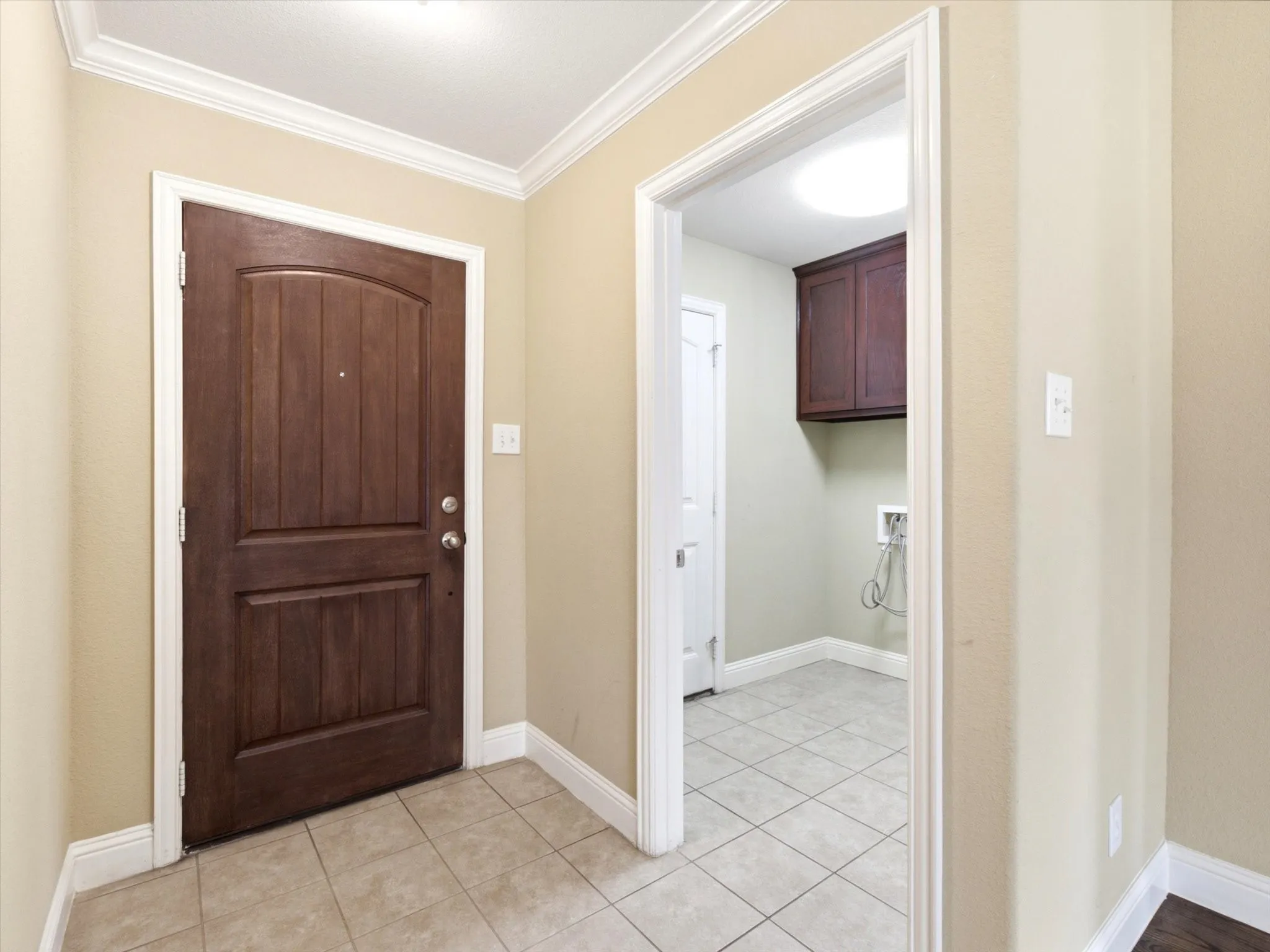 Entryway featuring a paneled wood door, crown molding, and tile flooring