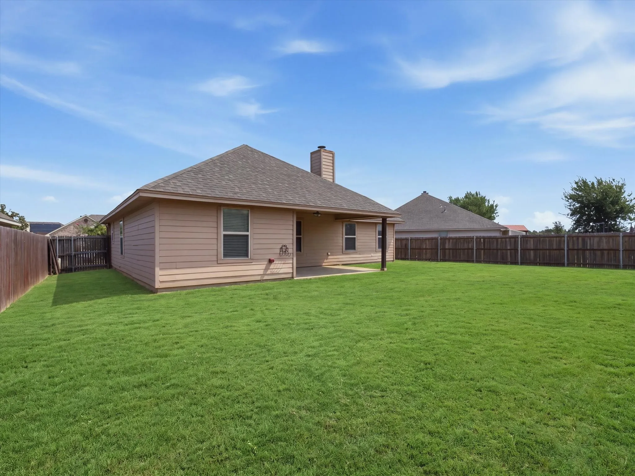 Charming single-story residence featuring a pitched roof with chimney, neutral exterior siding, and covered front entry