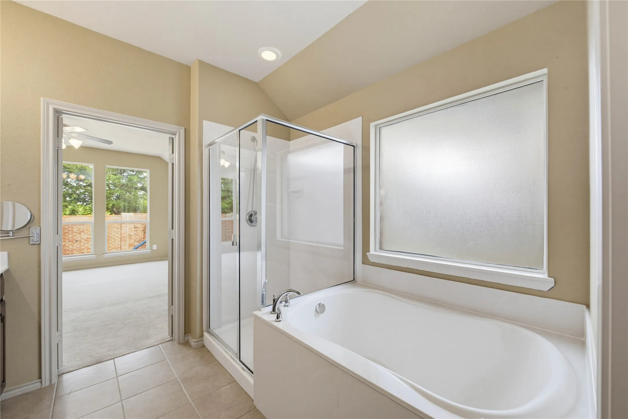Separate shower and garden tub with frosted privacy window in ensuite primary bathroom.