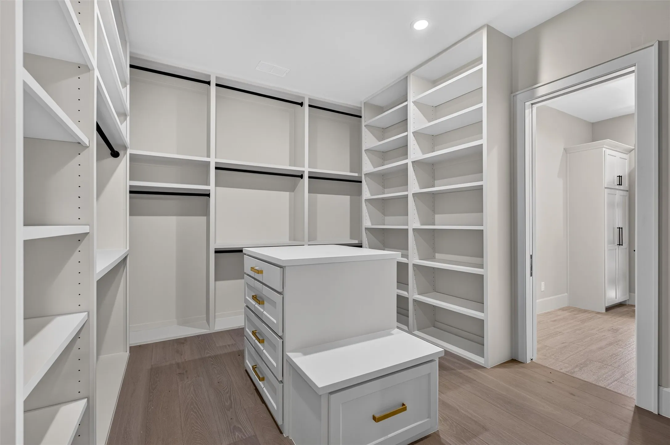 Custom primary closet with storage island that opens into laundry room.