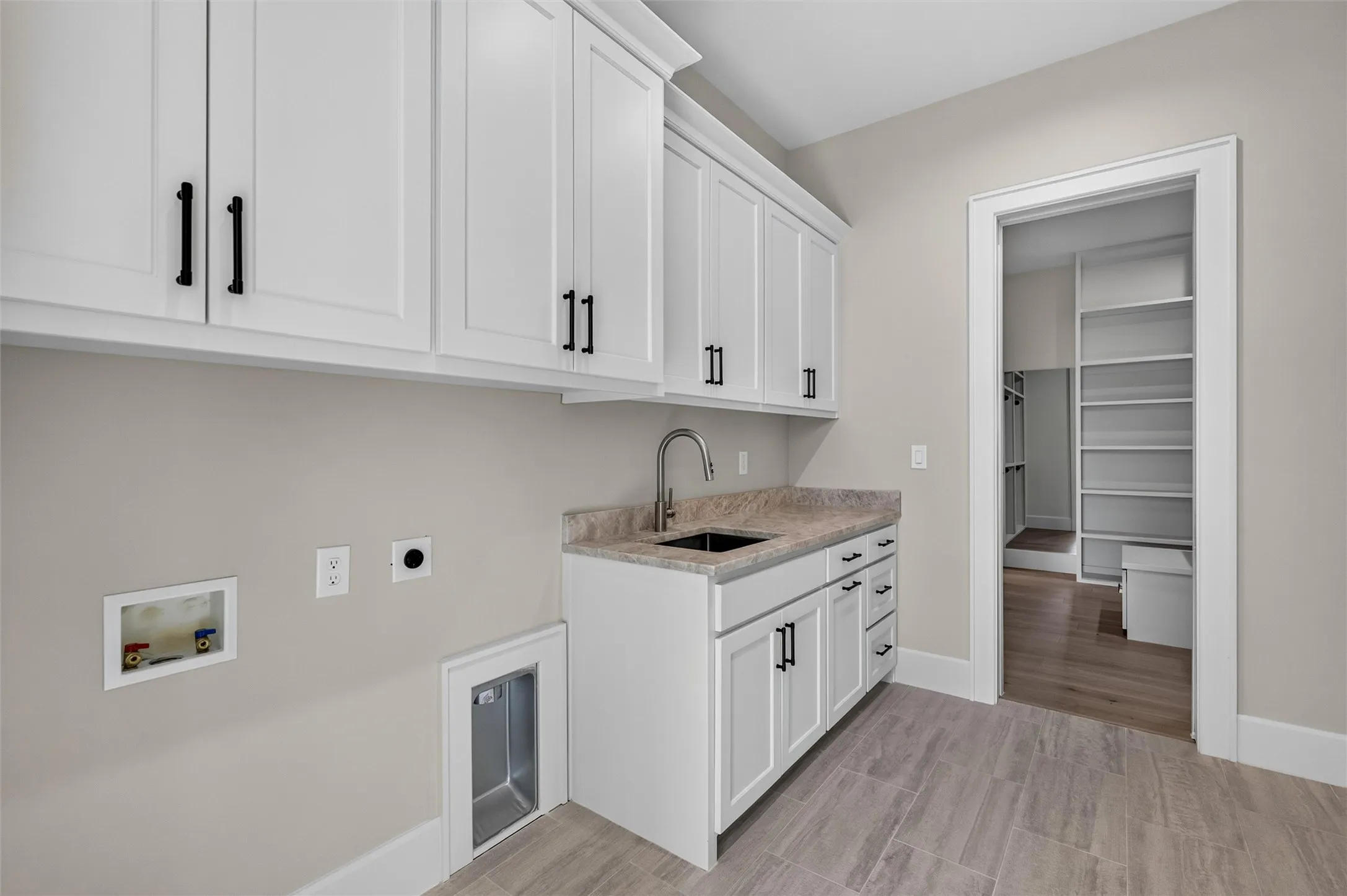 Laundry room, with an abundance of cabinetry, sink and direct access to the primary closet.