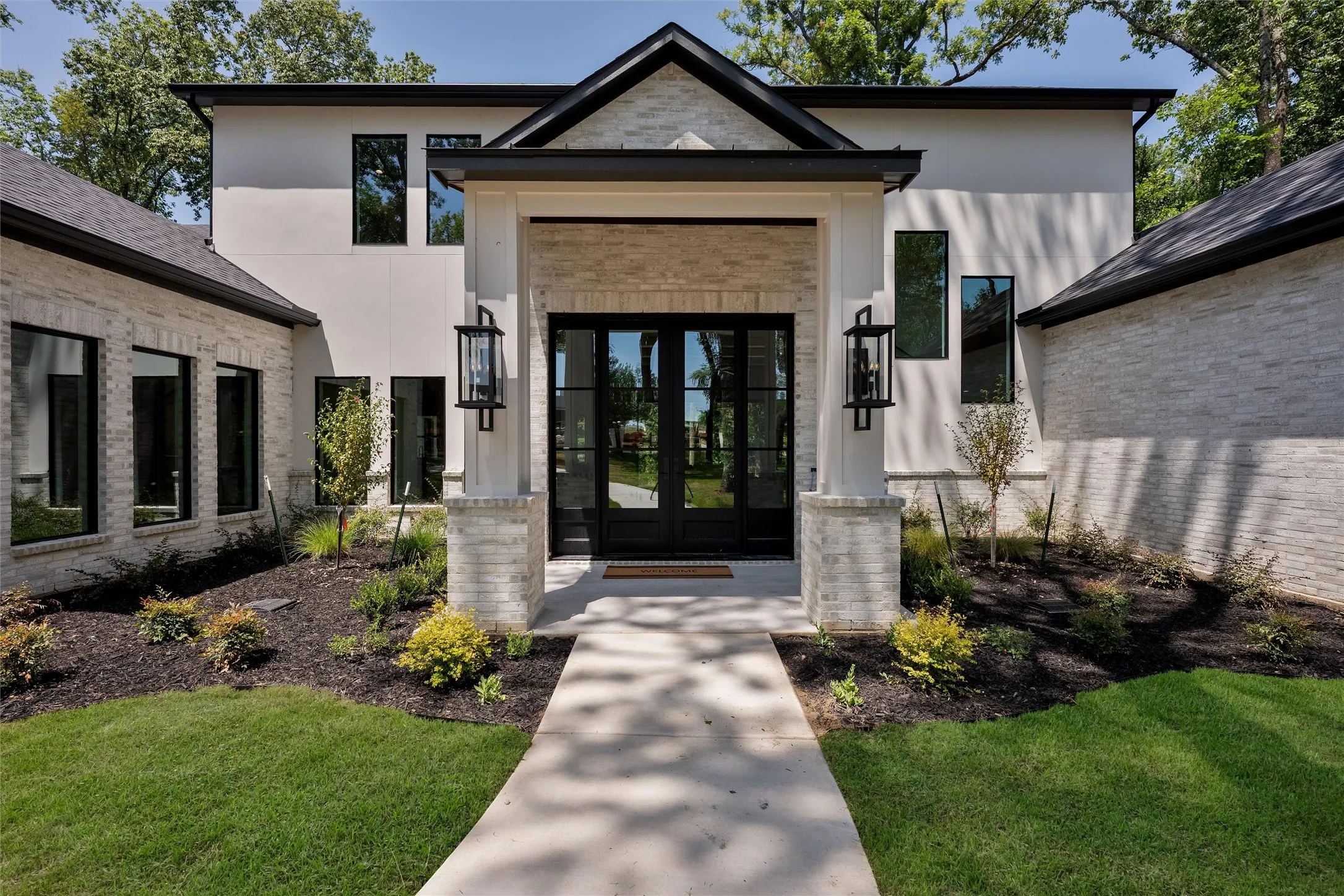 Covered entry with beautiful lighting and landscaping.