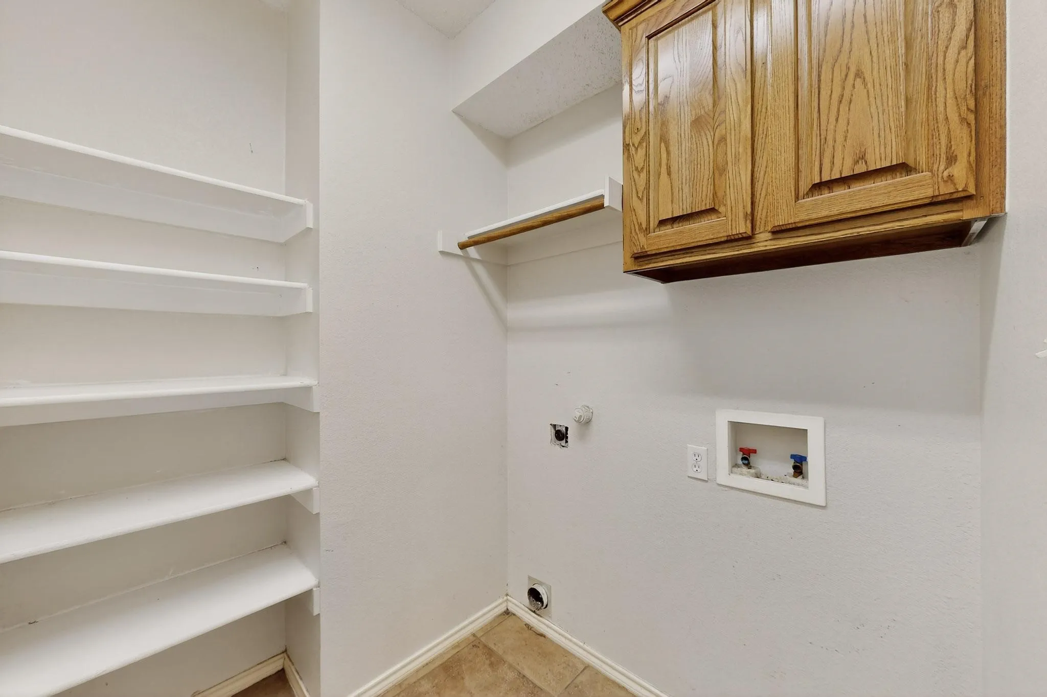 Laundry area with cabinet space, hookup for an electric dryer, washer hookup, light tile patterned floors, and gas dryer hookup
