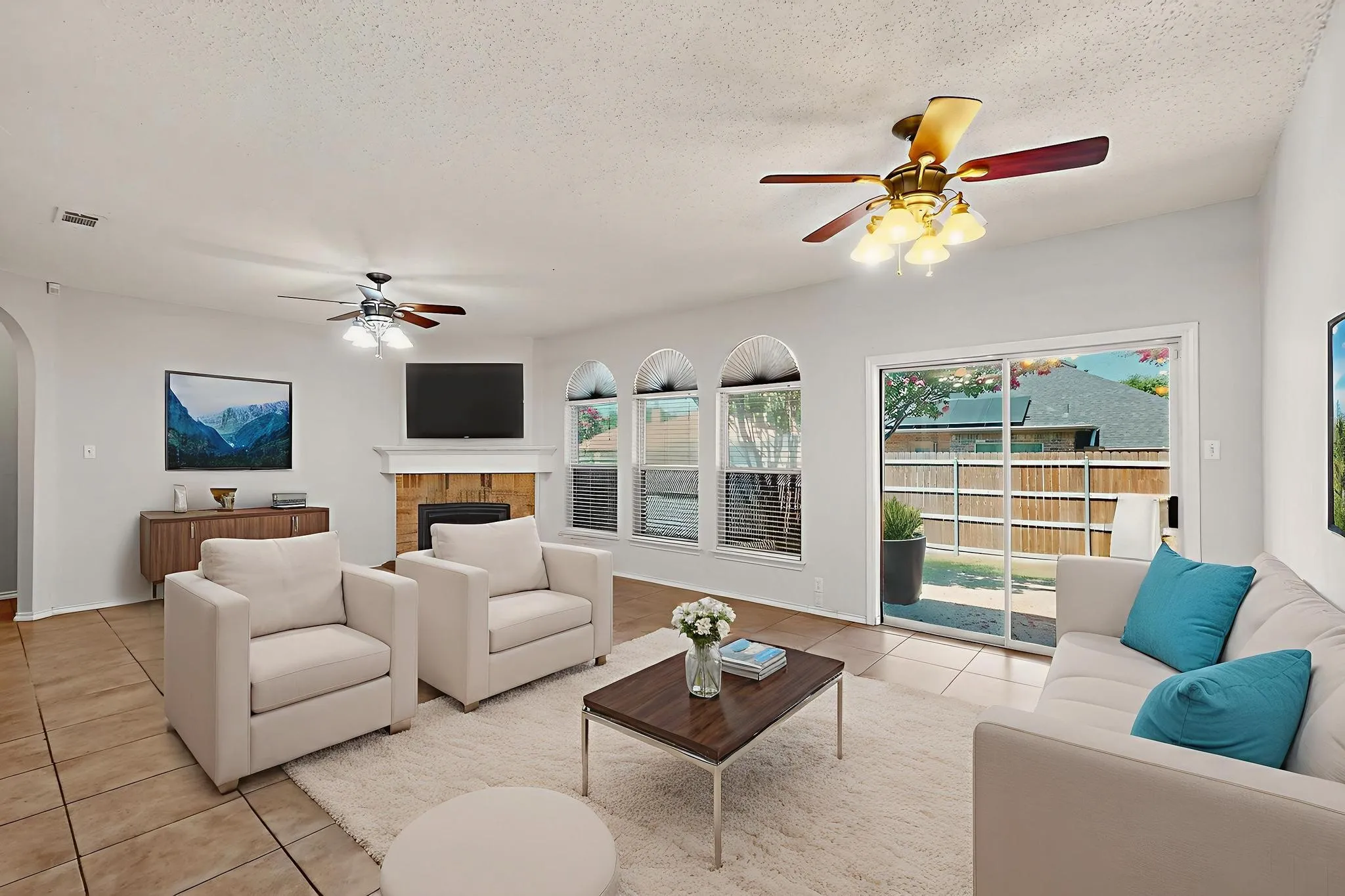 Living room featuring ceiling fan, light tile patterned floors, arched walkways, a brick fireplace, and a textured ceiling  *Virtually staged