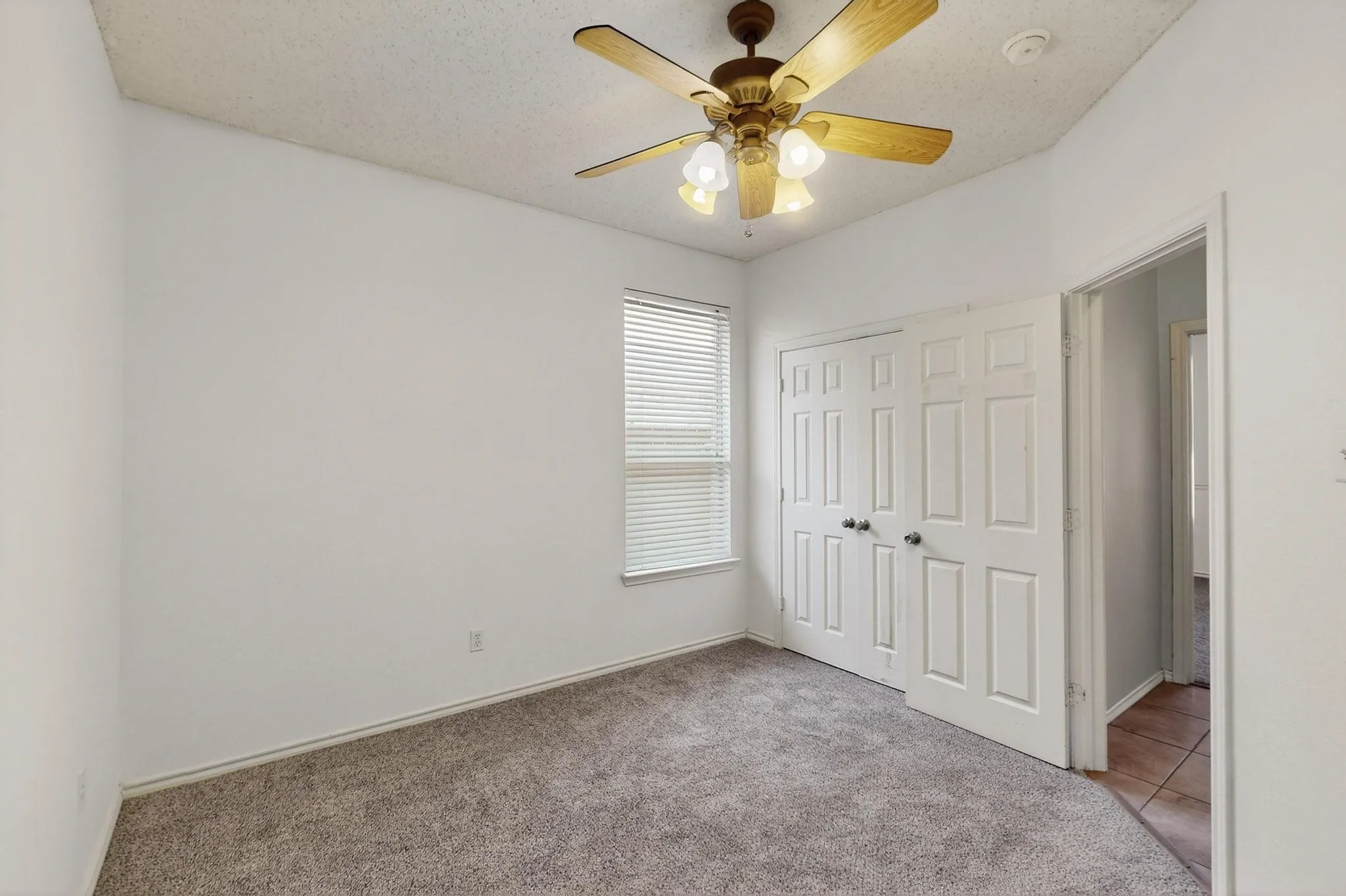 Unfurnished bedroom featuring light colored carpet, a closet, and ceiling fan
