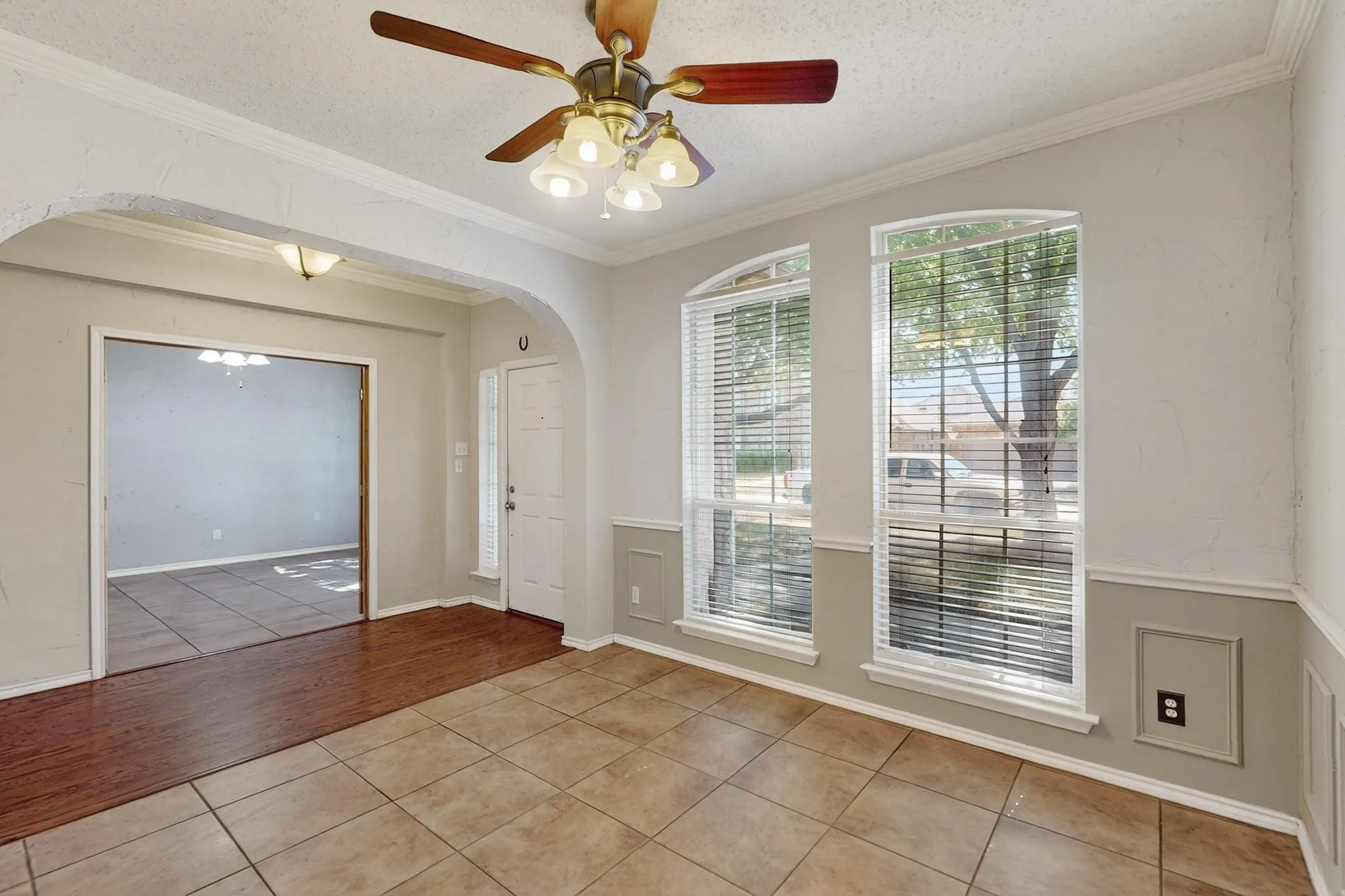 Foyer entrance featuring light tile patterned floors, arched walkways, crown molding, a ceiling fan, and a textured ceiling