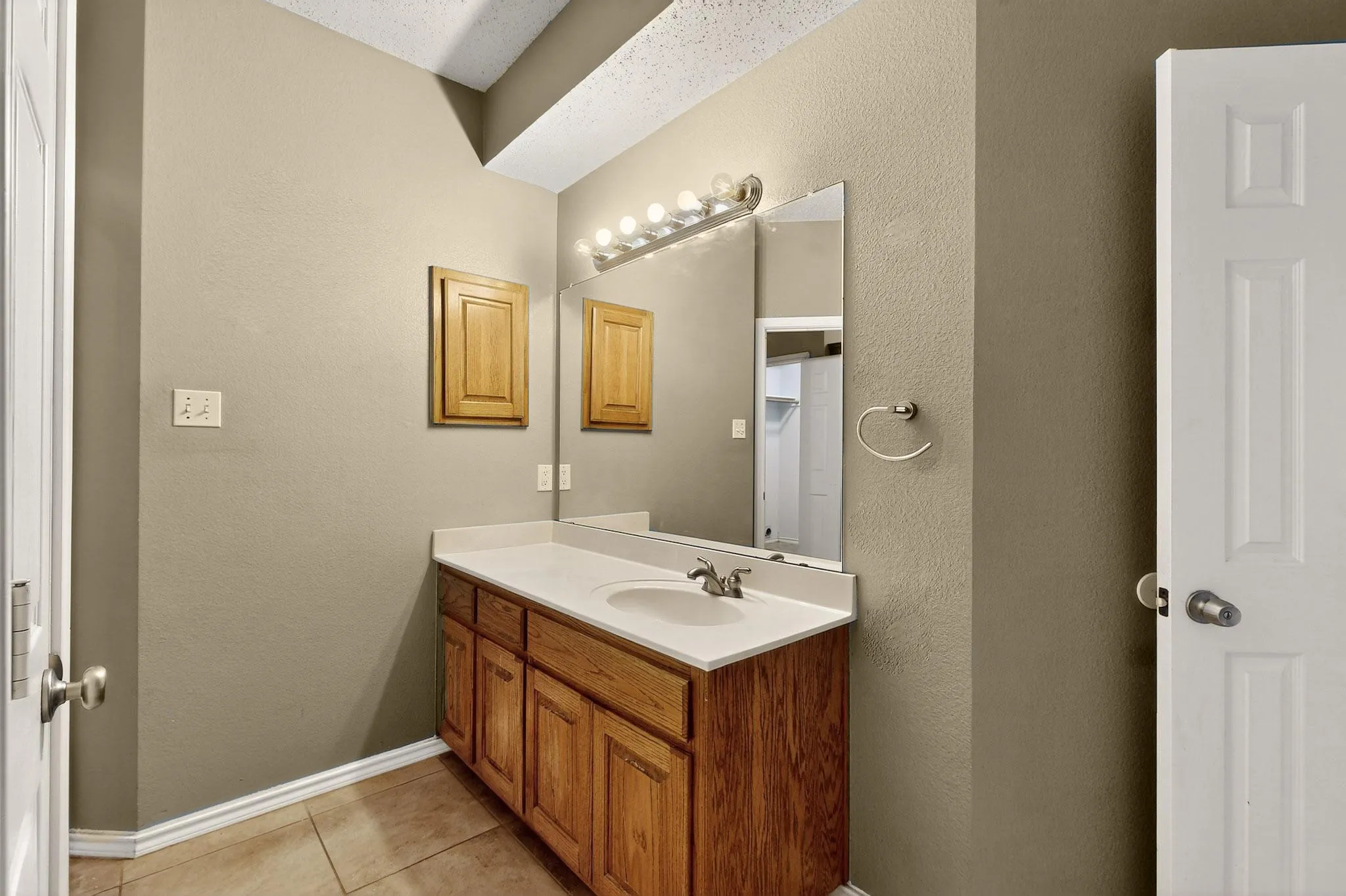 Bathroom featuring tile patterned flooring, vanity, and a textured wall
