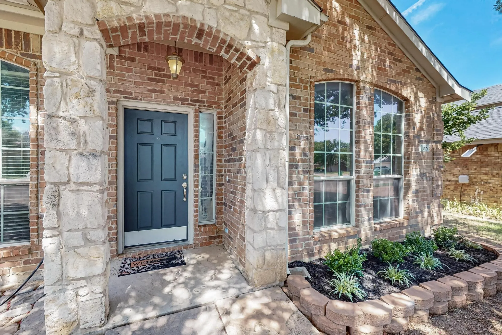 View of exterior entry featuring brick siding and stone siding