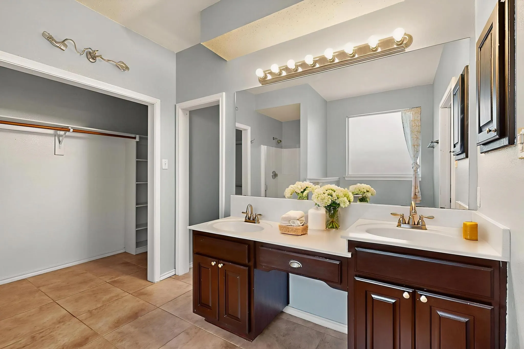 Bathroom featuring double vanity, a shower, a walk in closet, and tile patterned floors  *Virtually staged