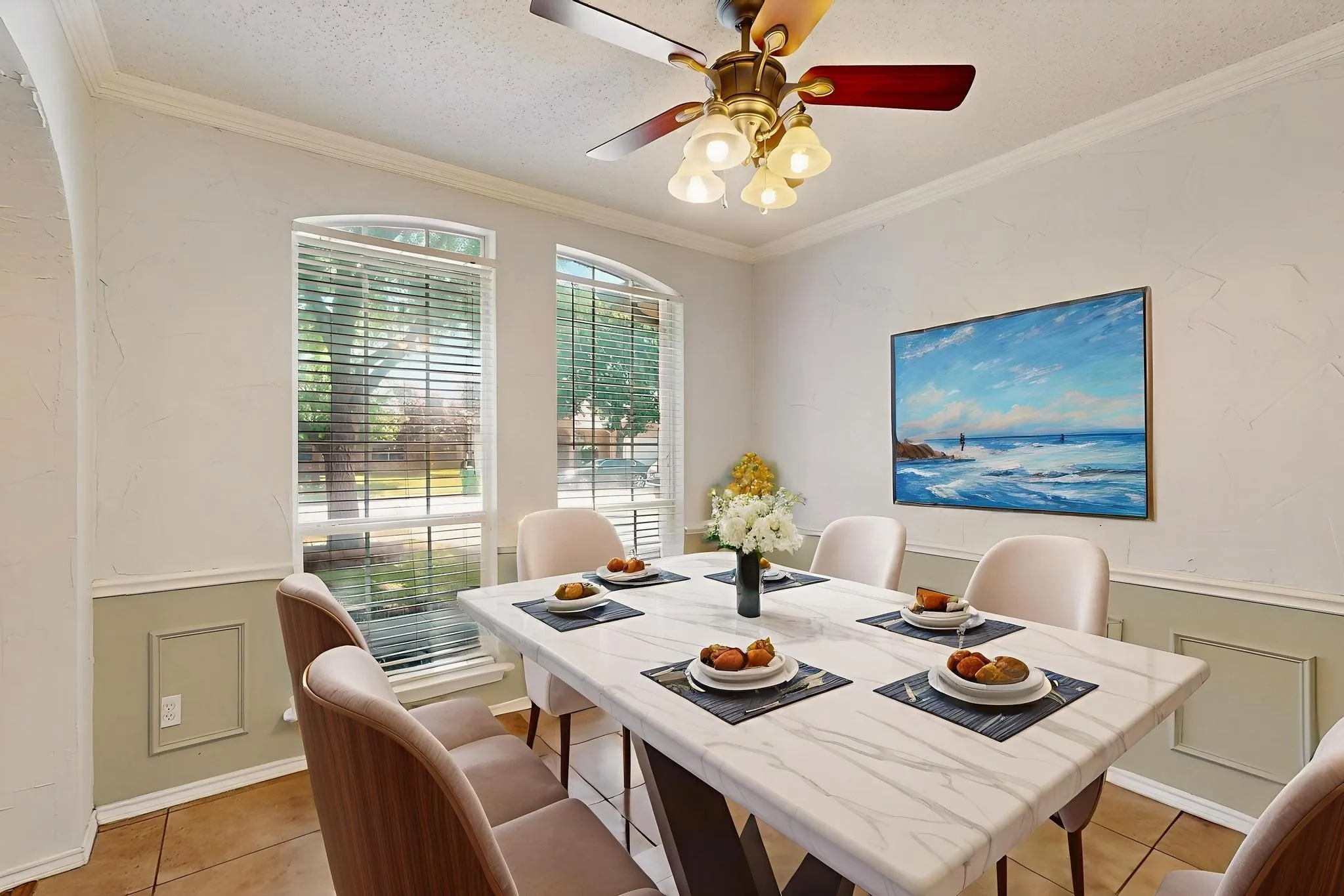 Dining space featuring light tile patterned floors, crown molding, a ceiling fan, and wainscoting  *Virtually staged