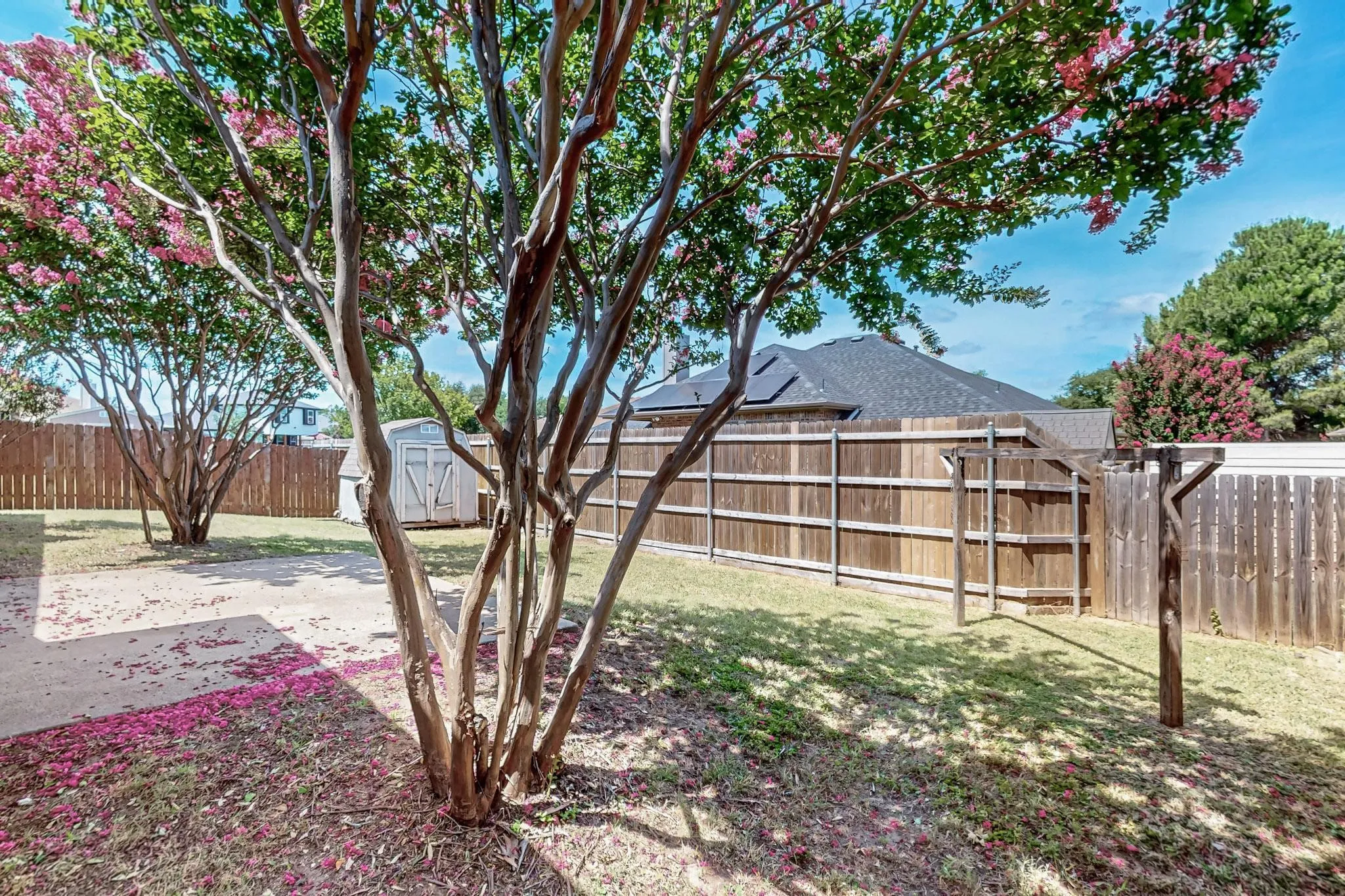 Fenced backyard featuring a storage unit and a patio