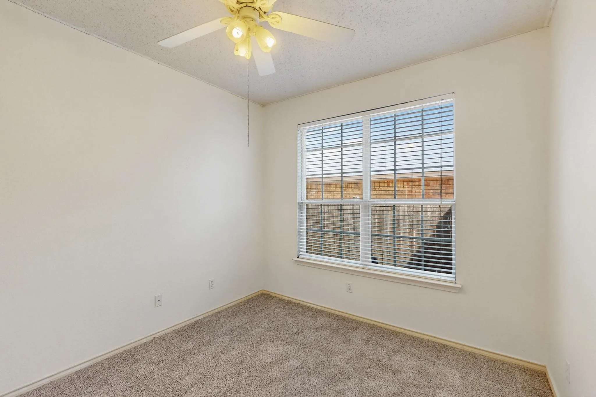 Carpeted empty room with a textured ceiling and ceiling fan