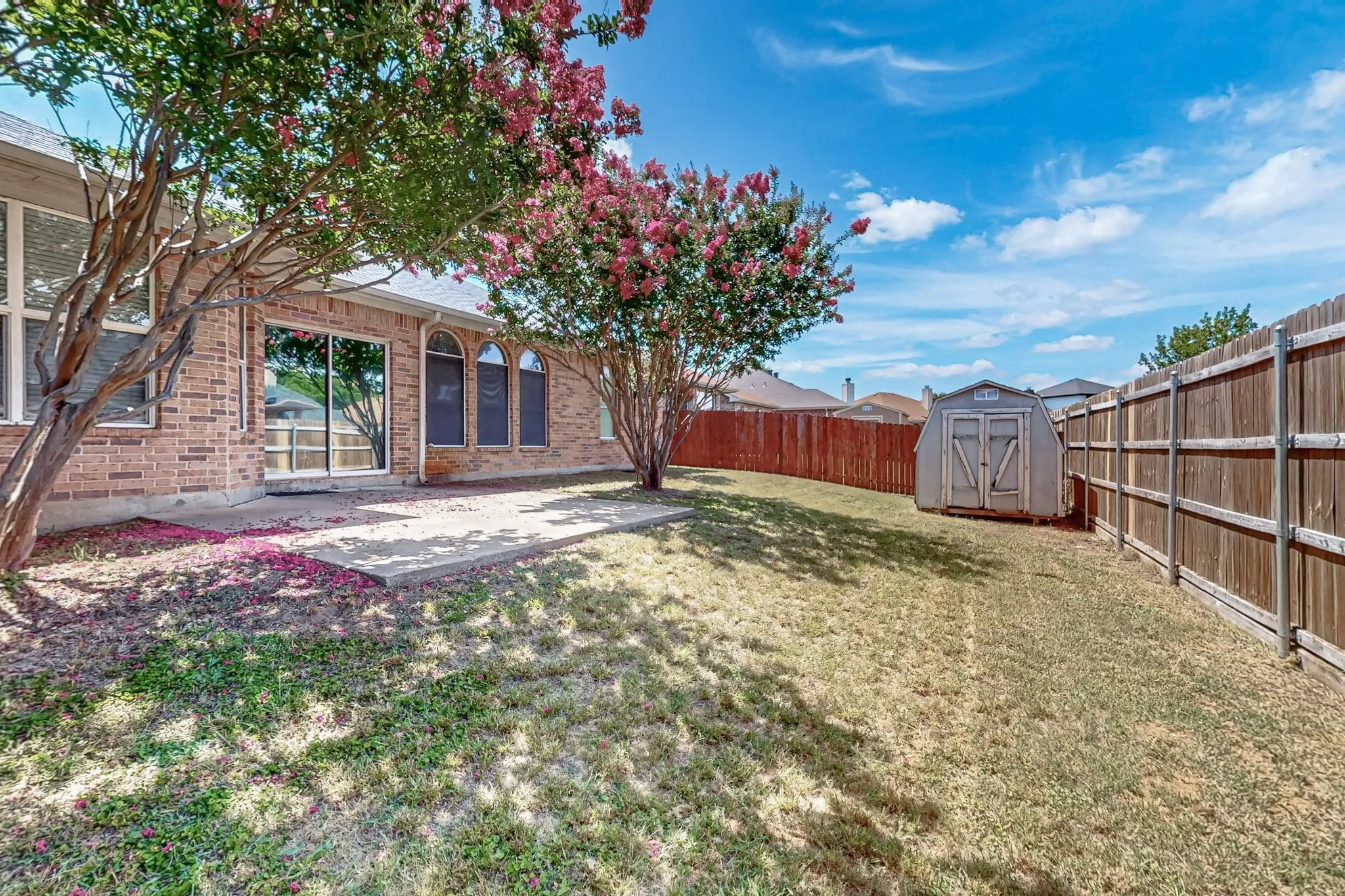 Fenced backyard featuring a shed and a patio
