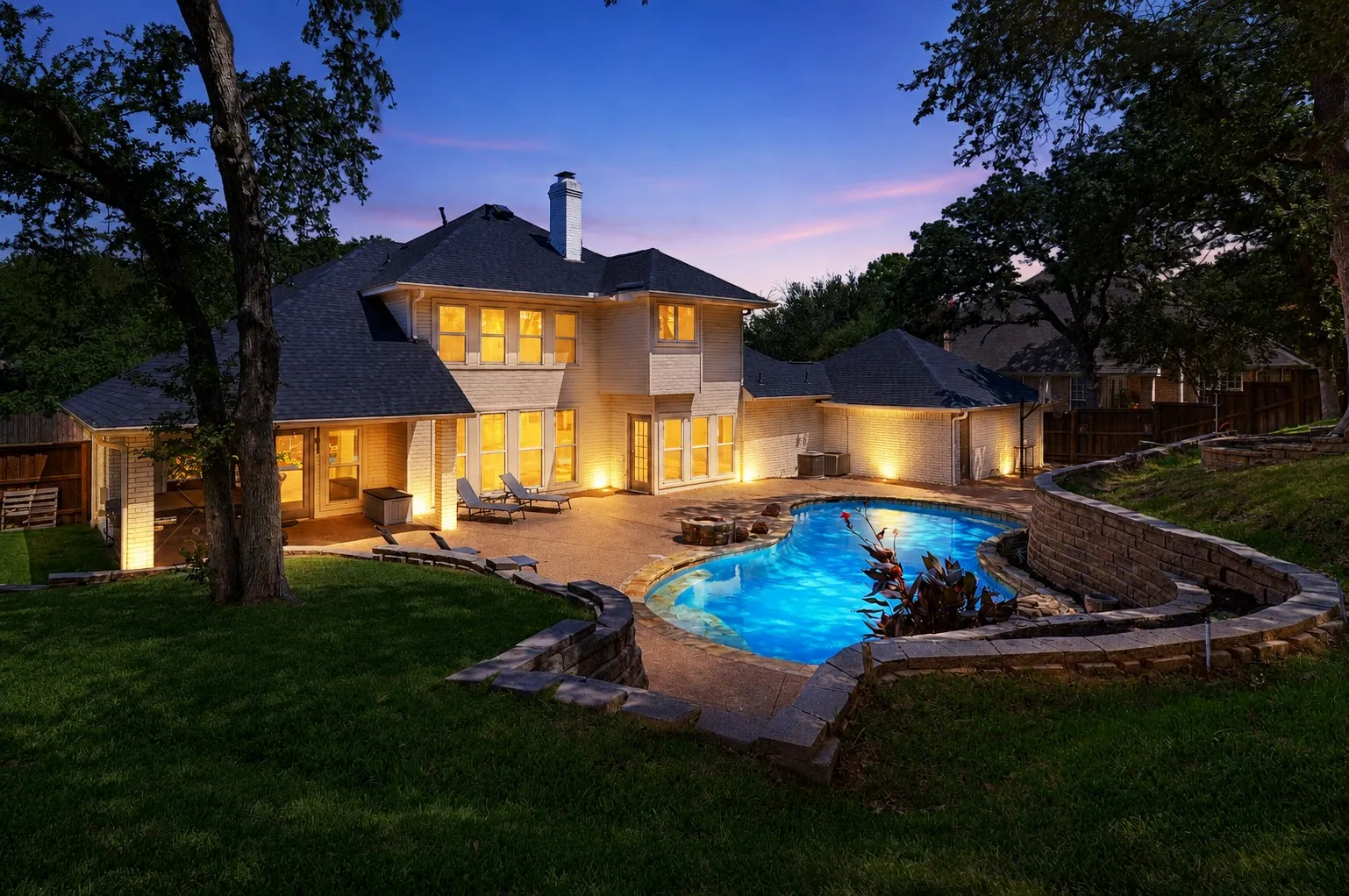 Custom-shaped swimming pool featuring a rock waterfall and integrated spa