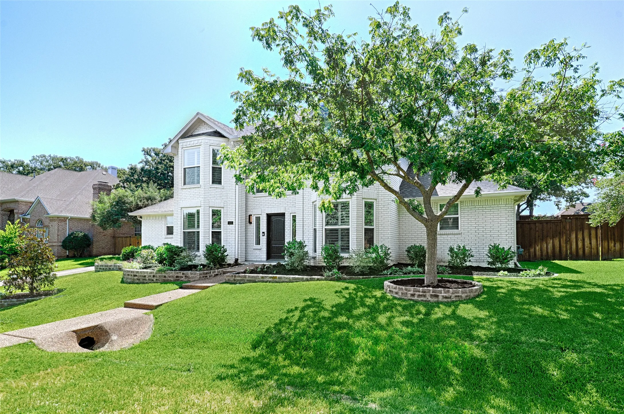 Two-story brick exterior with a bay window feature, dark entry door, and manicured landscaping