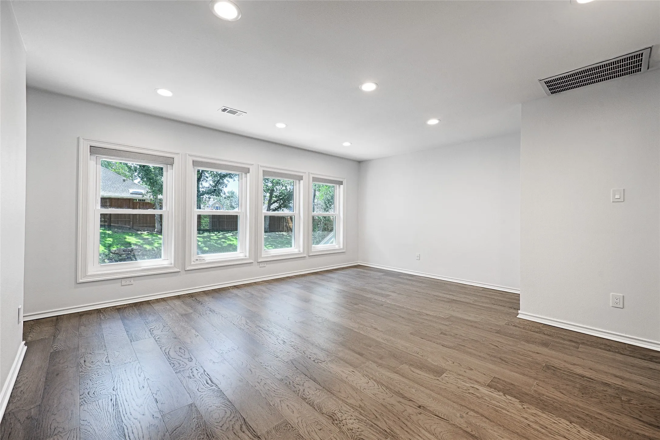 Spacious second-floor room featuring wood-finish flooring and a series of four windows with white trim