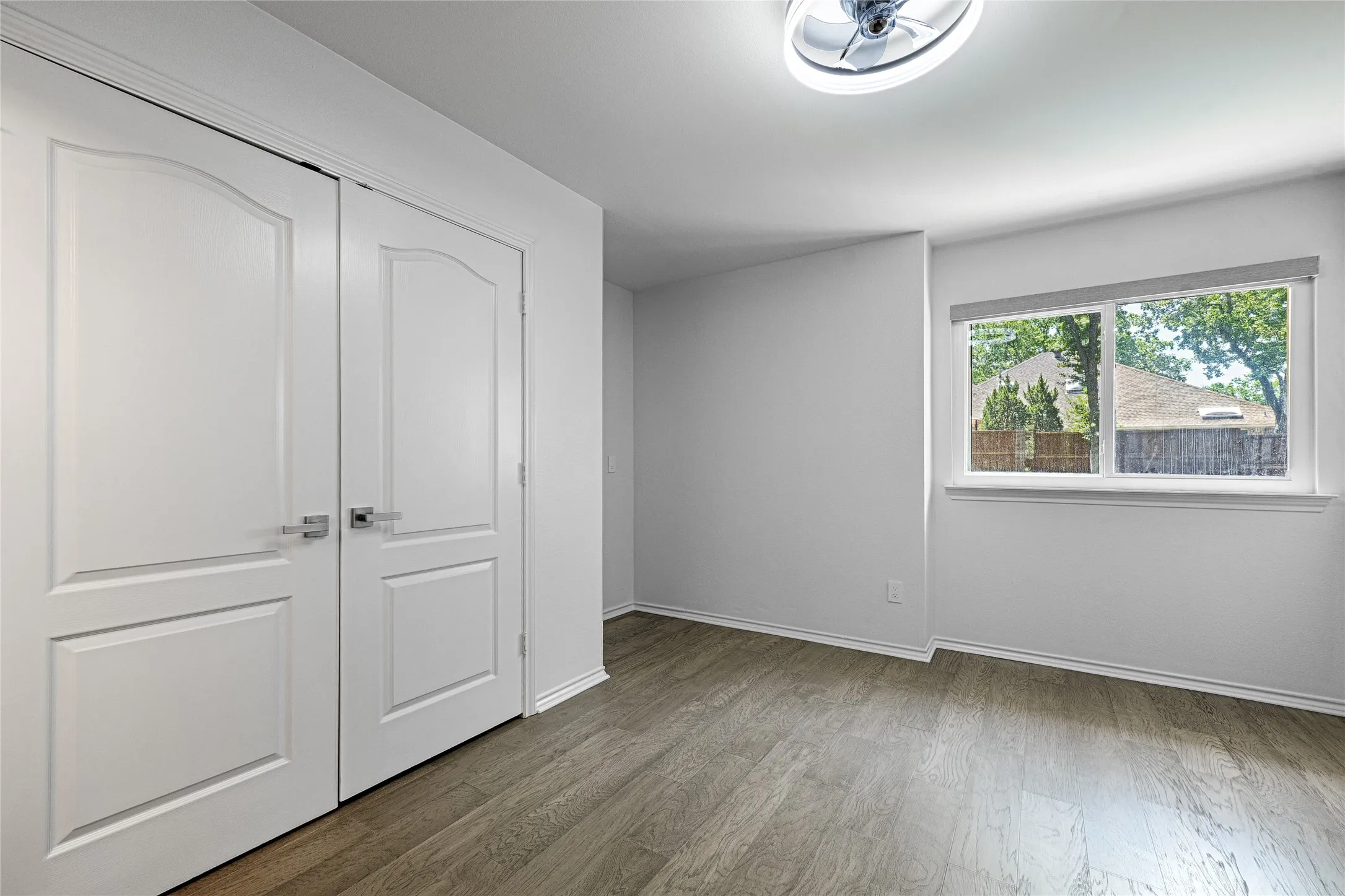 Bright room featuring wood-finish flooring and a contemporary ceiling light fixture