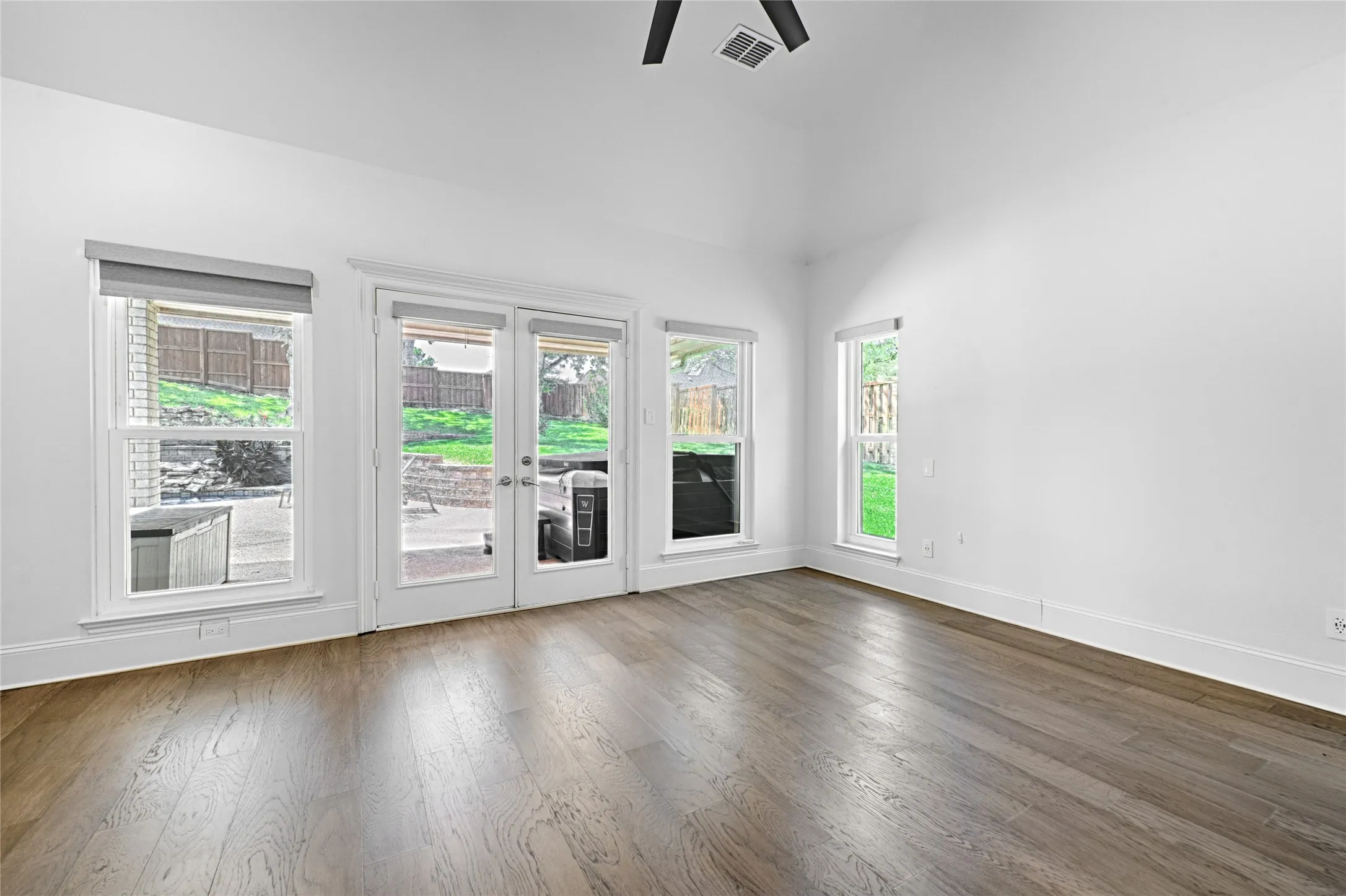 Vaulted ceiling bedroom with wood-finish flooring, featuring a ceiling fan and recessed lighting