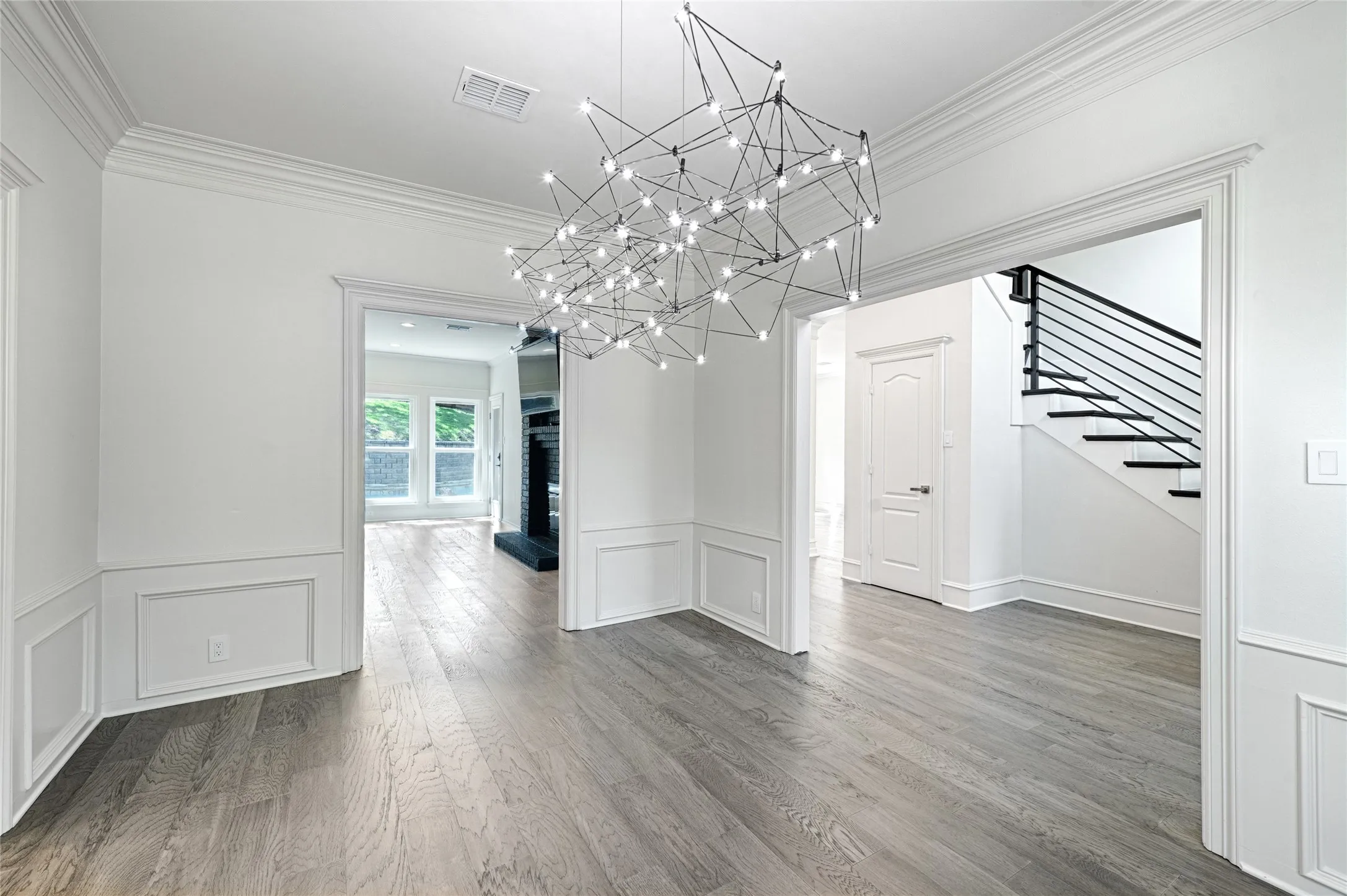 Open concept interior featuring wood-finish flooring and a contemporary linear chandelier