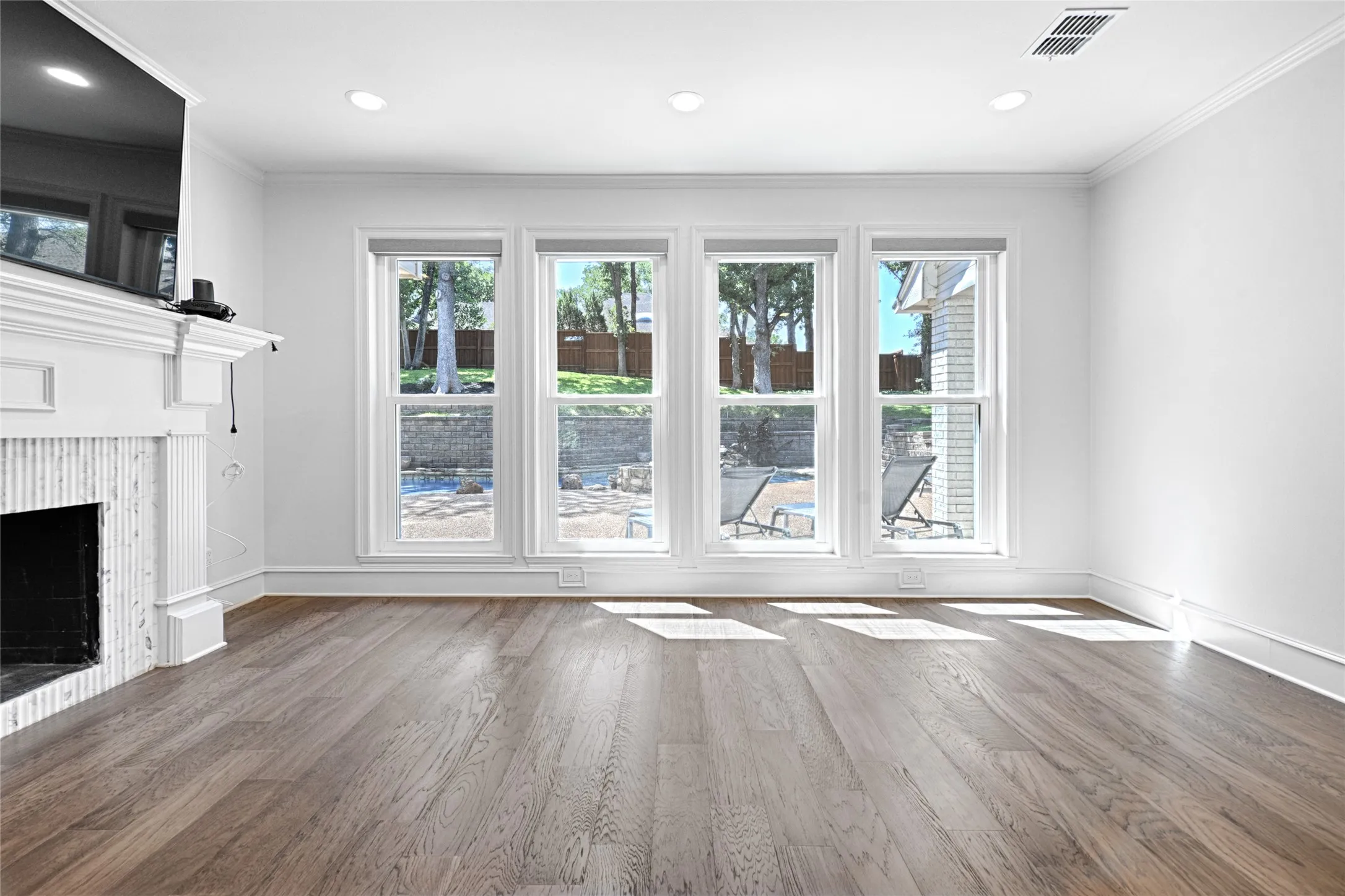 Spacious room featuring wood-finish flooring, recessed lighting, and crown molding