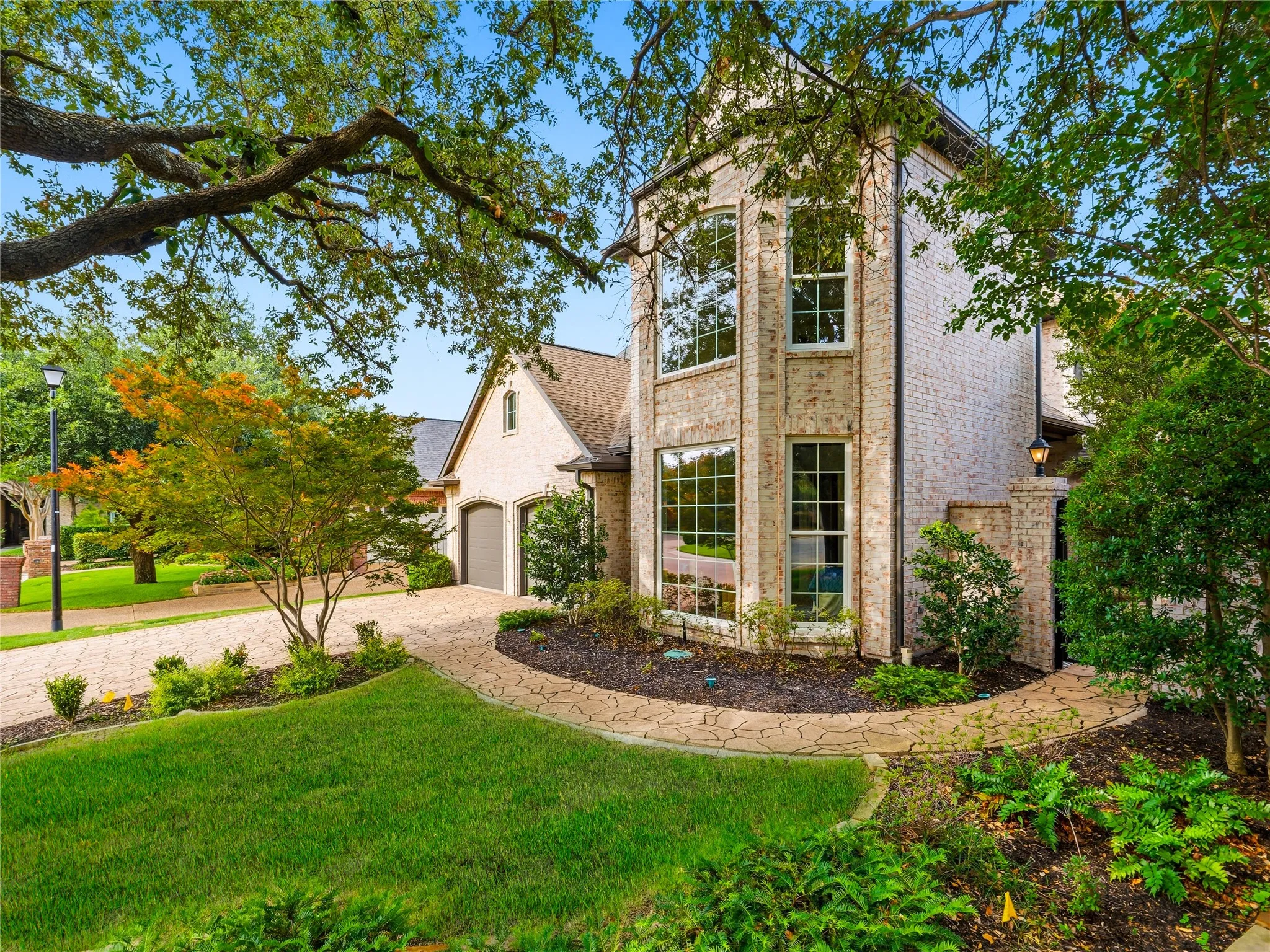 Stately brick residence featuring a prominent multi-story window bay, a stone pathway, and a well-maintained lawn