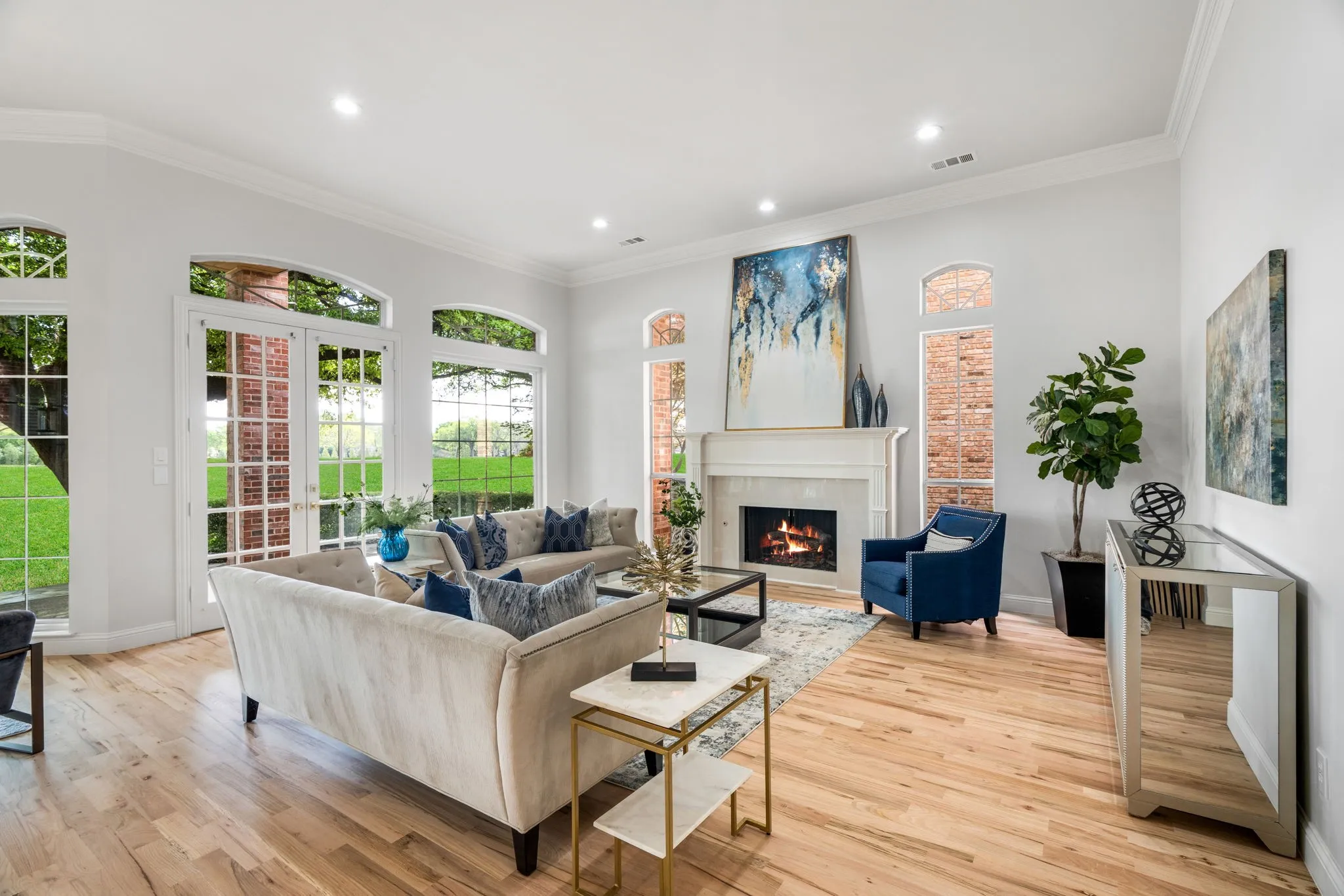 Living room with ornamental molding, light wood finished floors, a lit fireplace, healthy amount of natural light, and recessed lighting