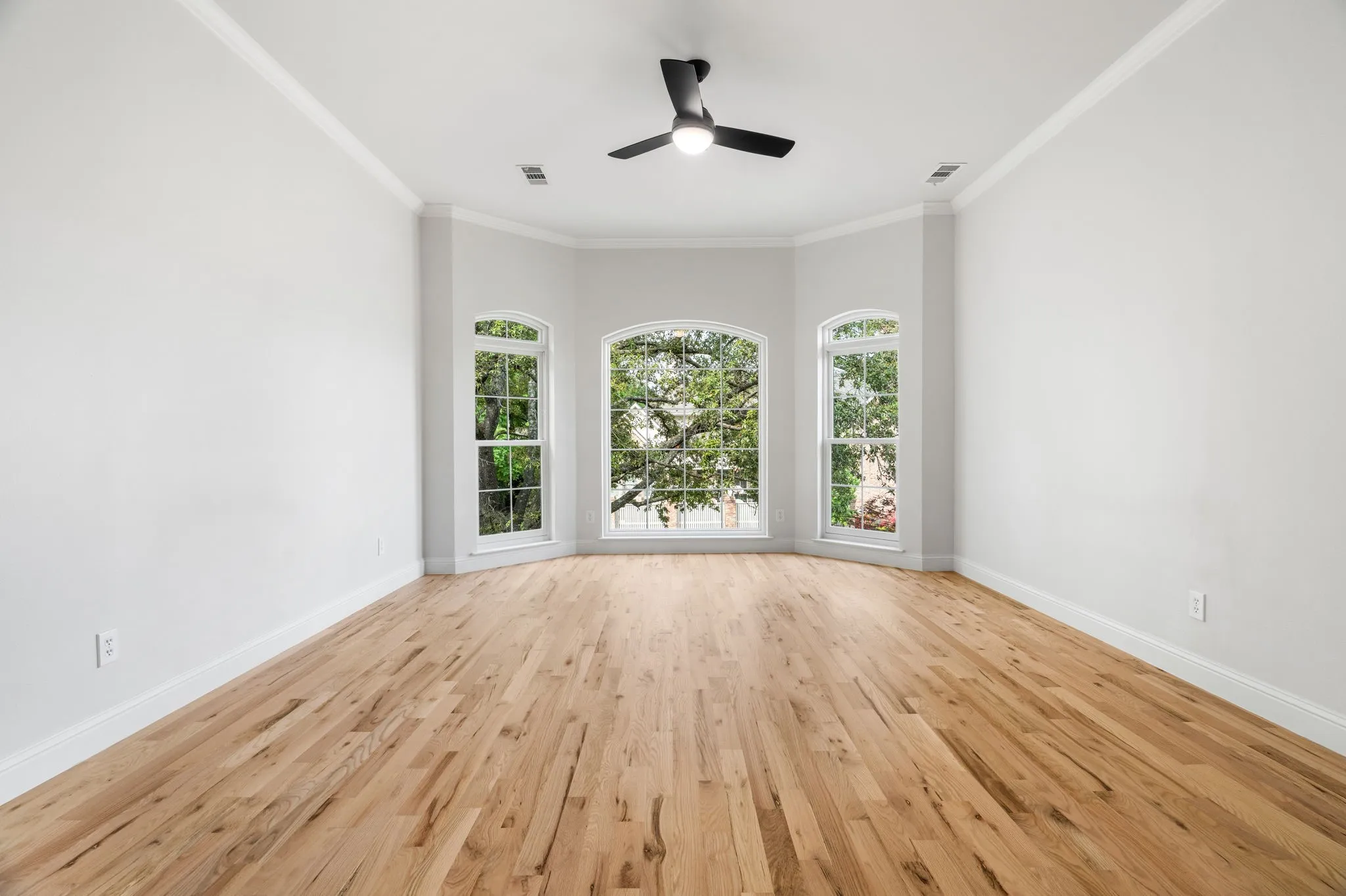 Unfurnished room featuring light wood-style floors, ceiling fan, ornamental molding, and healthy amount of natural light