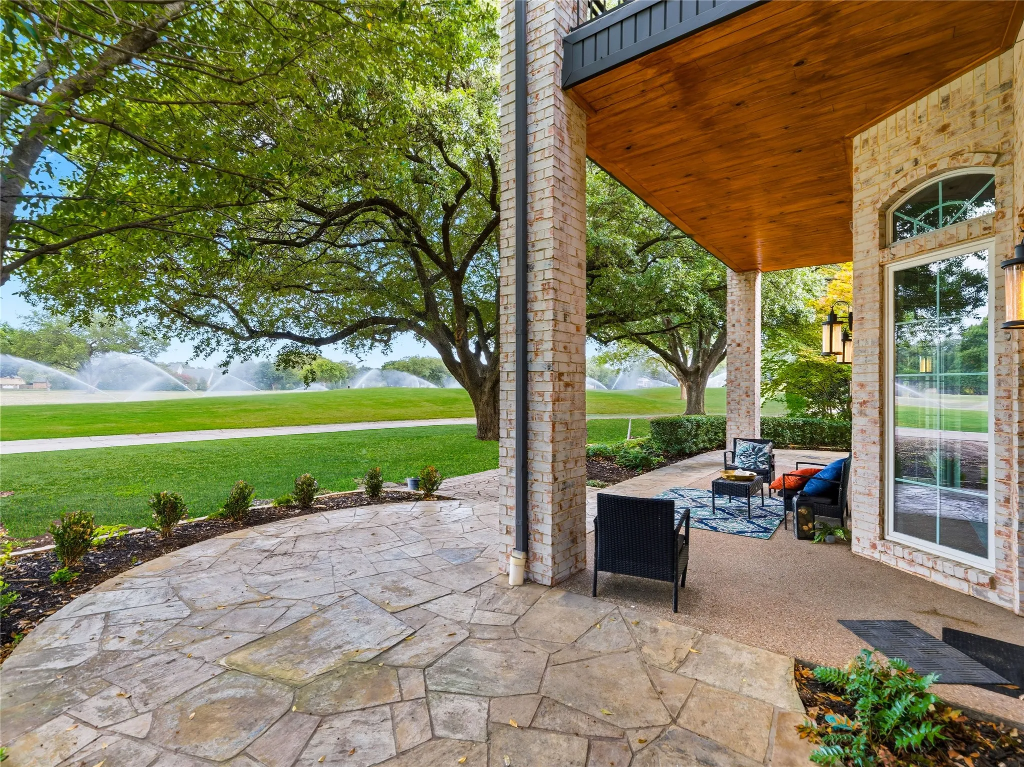 Brick exterior featuring a covered patio with wood-finish ceiling and stone flooring
