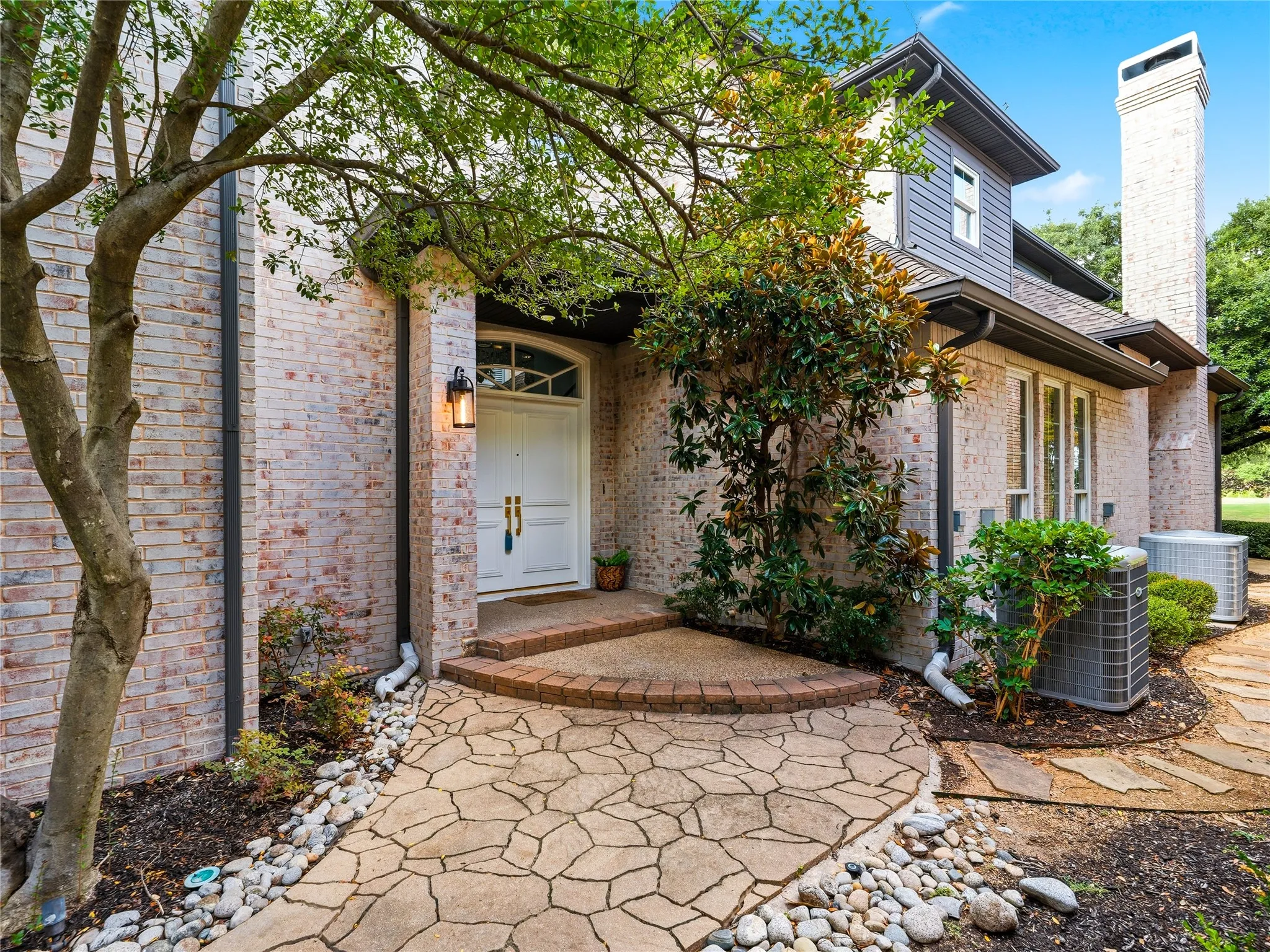 Stone tile walkway leading to an arched entry with a white paneled door