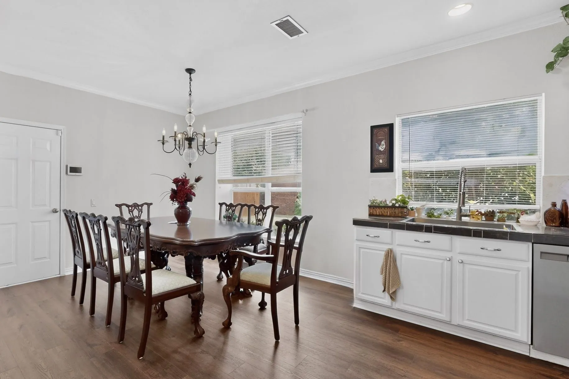 Dining area featuring wood-finish flooring, a chandelier, and crown molding