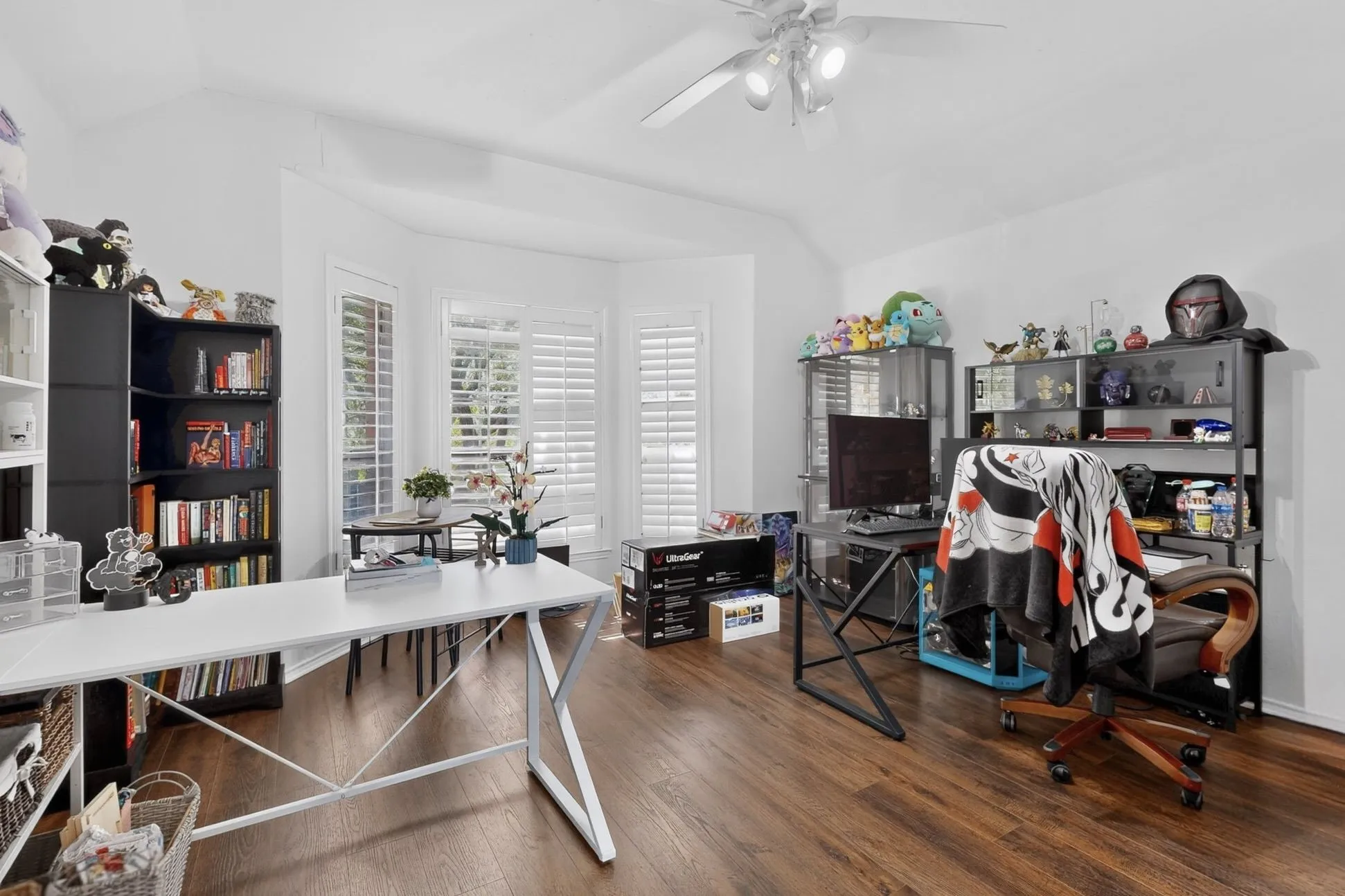 Room featuring wood-finish flooring, white walls, and a vaulted ceiling with a ceiling fan light fixture