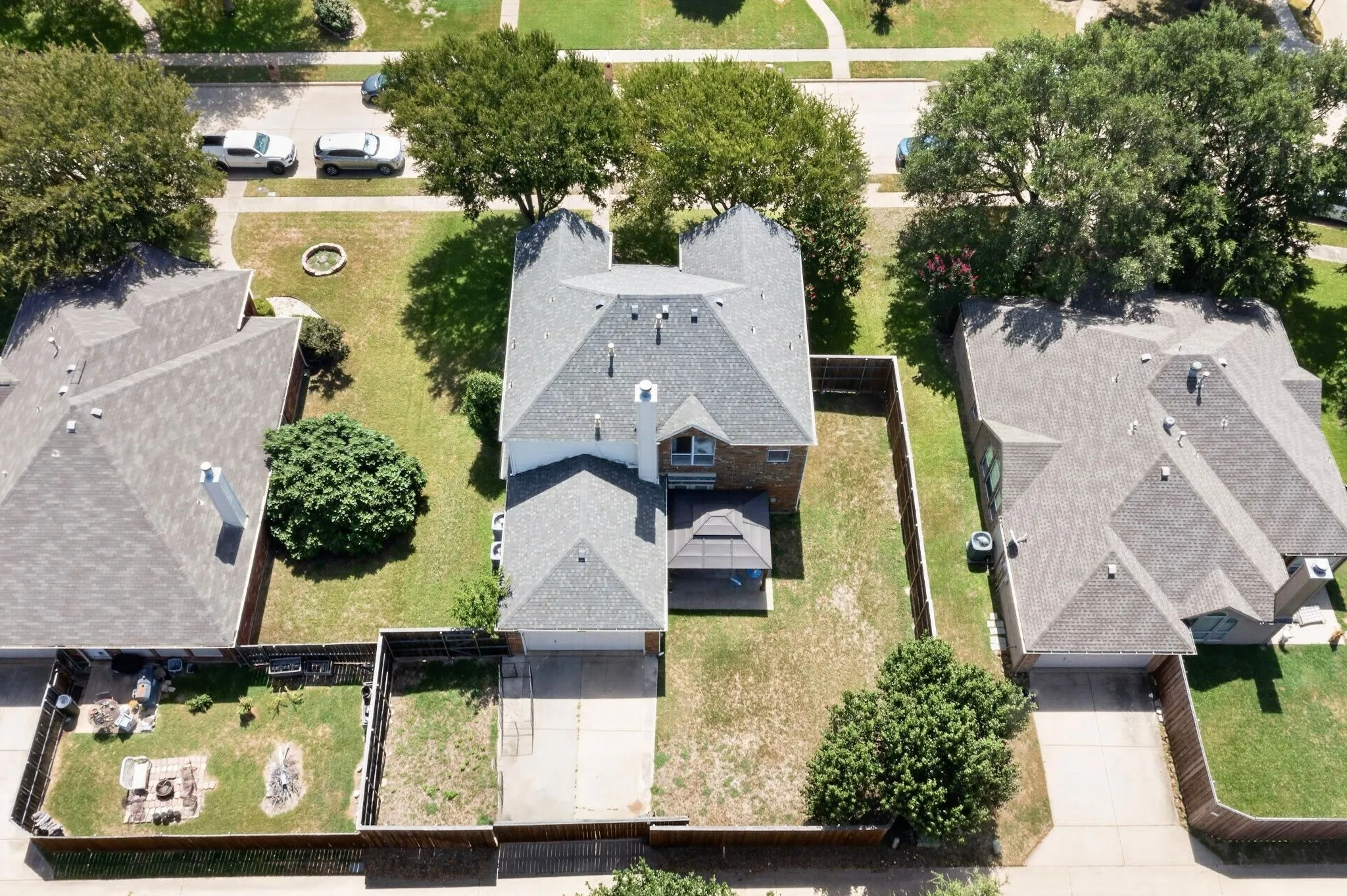Two-story residence featuring a gray shingle roof and a fenced backyard