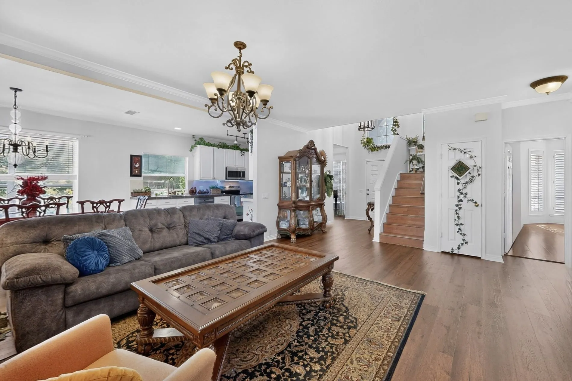 Open-concept living area featuring wood-finish flooring, a grand staircase with wood treads, and white wall finishes