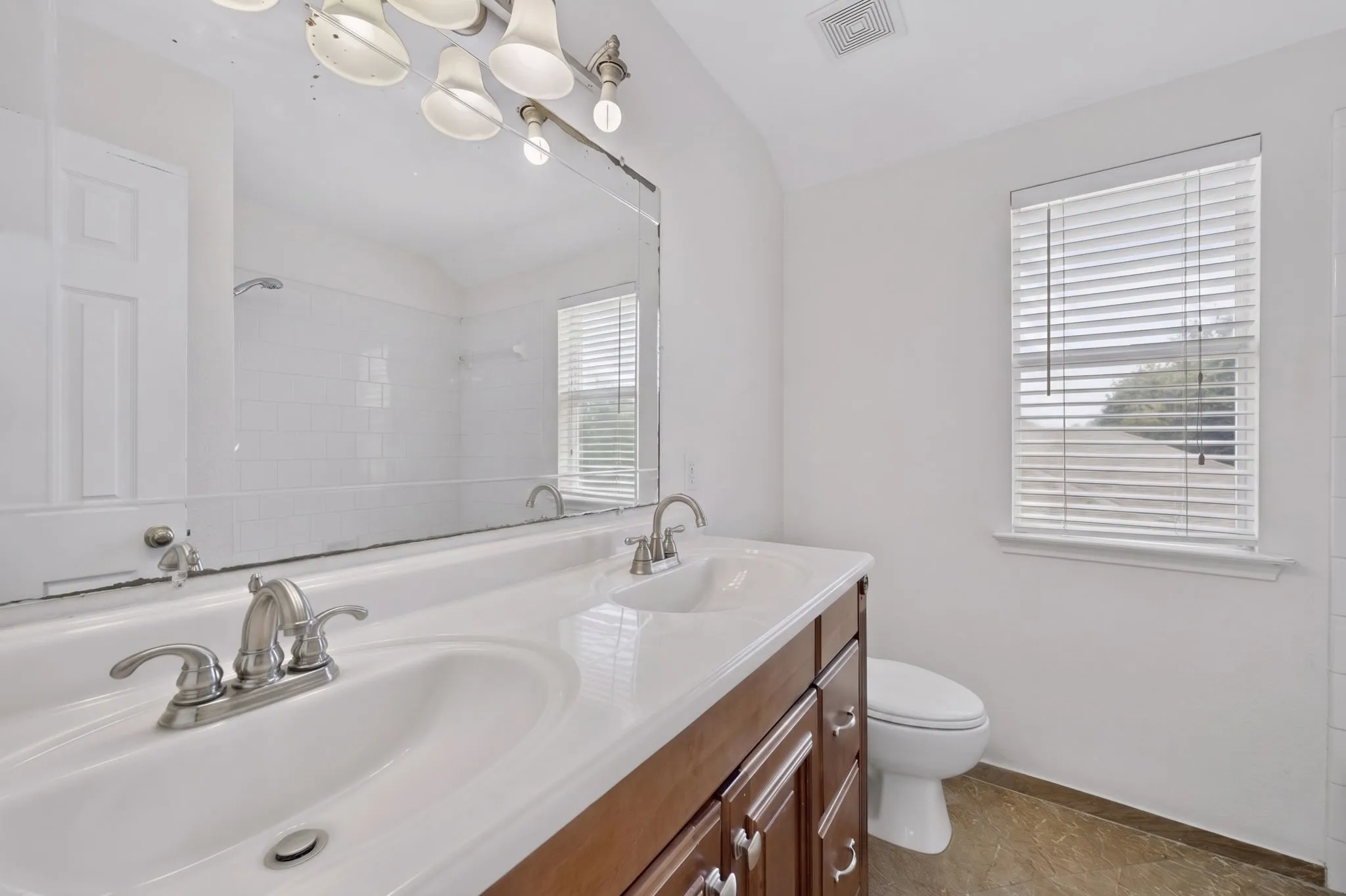 Bathroom featuring a dual-sink vanity with a white countertop and wood-finish cabinetry