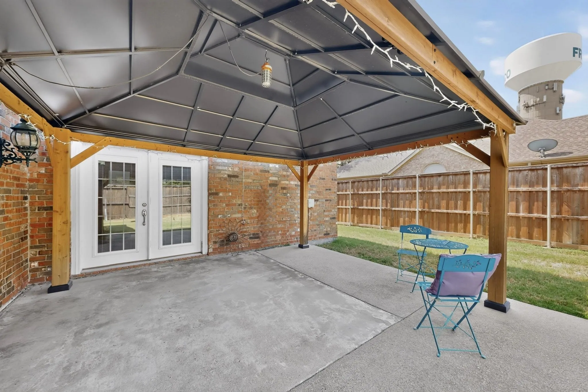 Covered patio space featuring a concrete slab, wooden support beams, and a dark metal gazebo roof