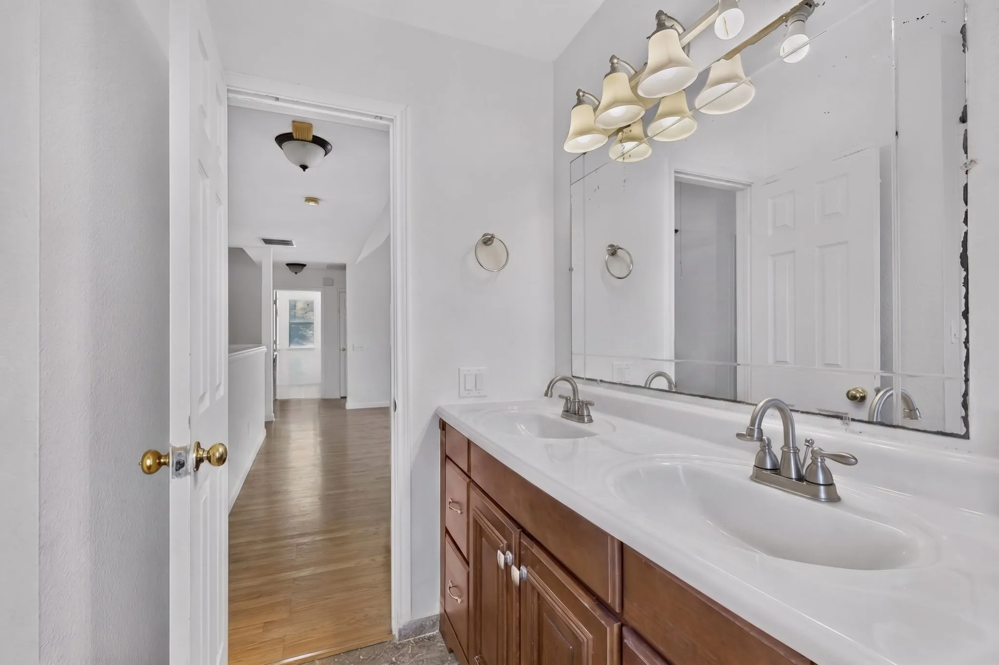 Dual sink vanity with white countertop, chrome faucets, and wood-finish cabinetry