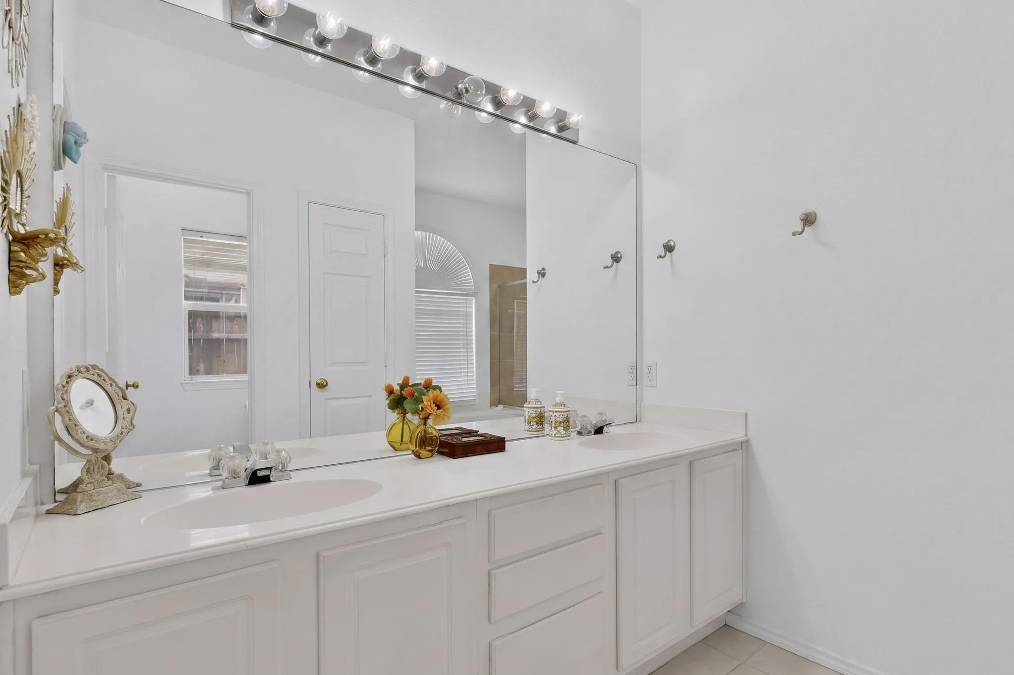 Dual vanity featuring white cabinetry, integrated sinks, chrome faucets, and a full-width mirror