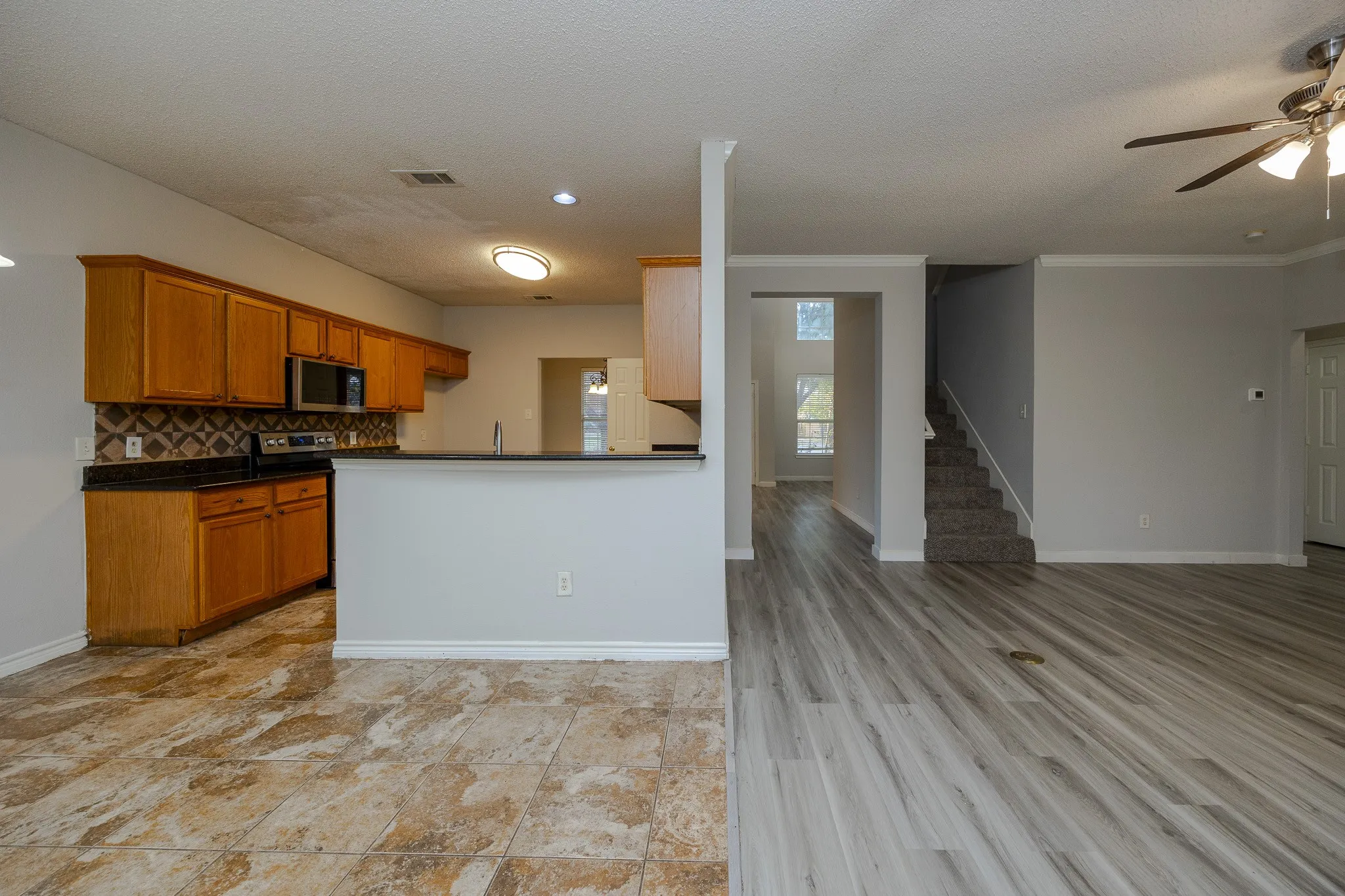 Kitchen with wood cabinetry, stainless steel appliances, and dark countertops