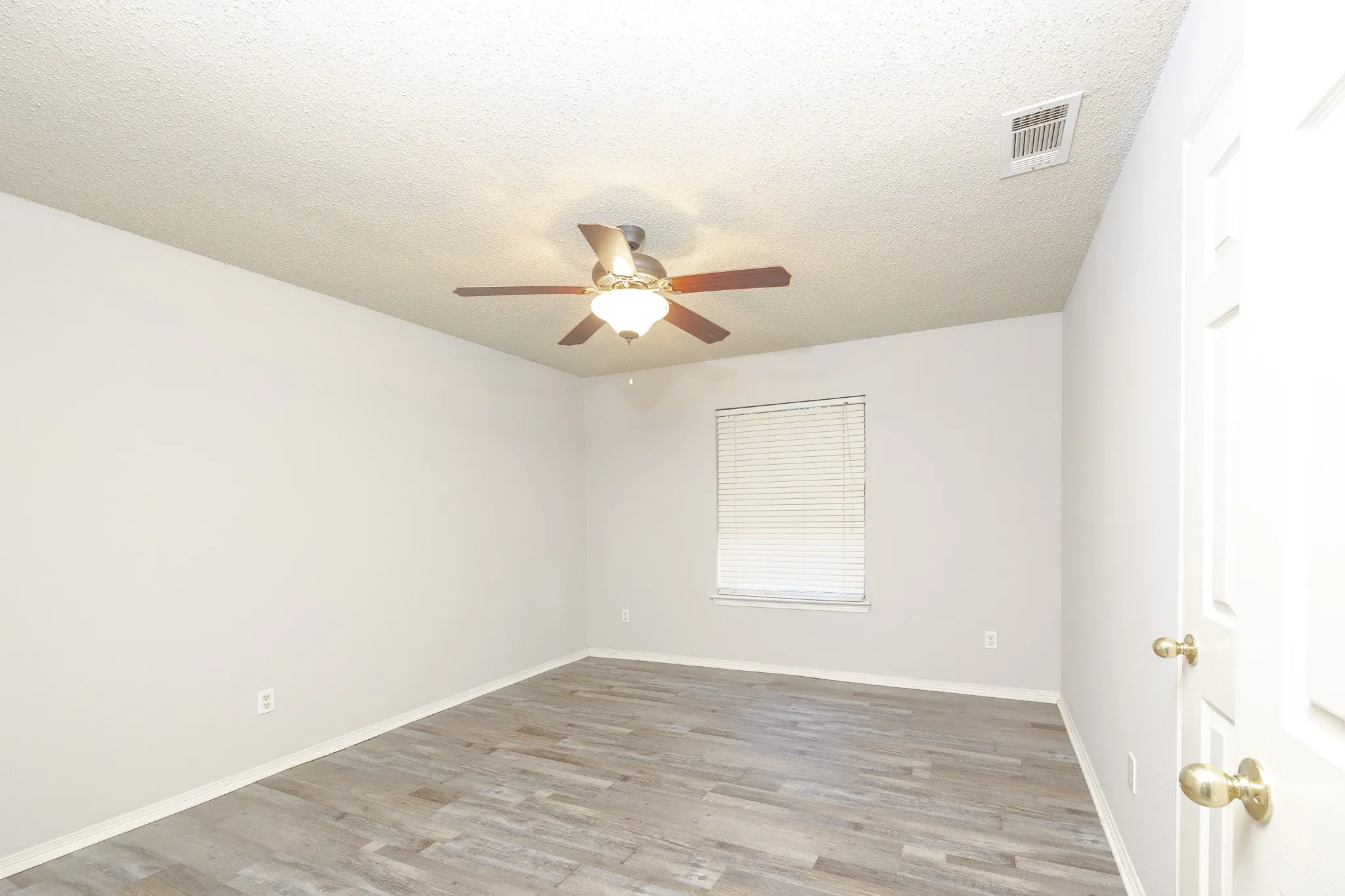 Wood-finish flooring, ceiling fan with integrated lighting, and window with blinds
