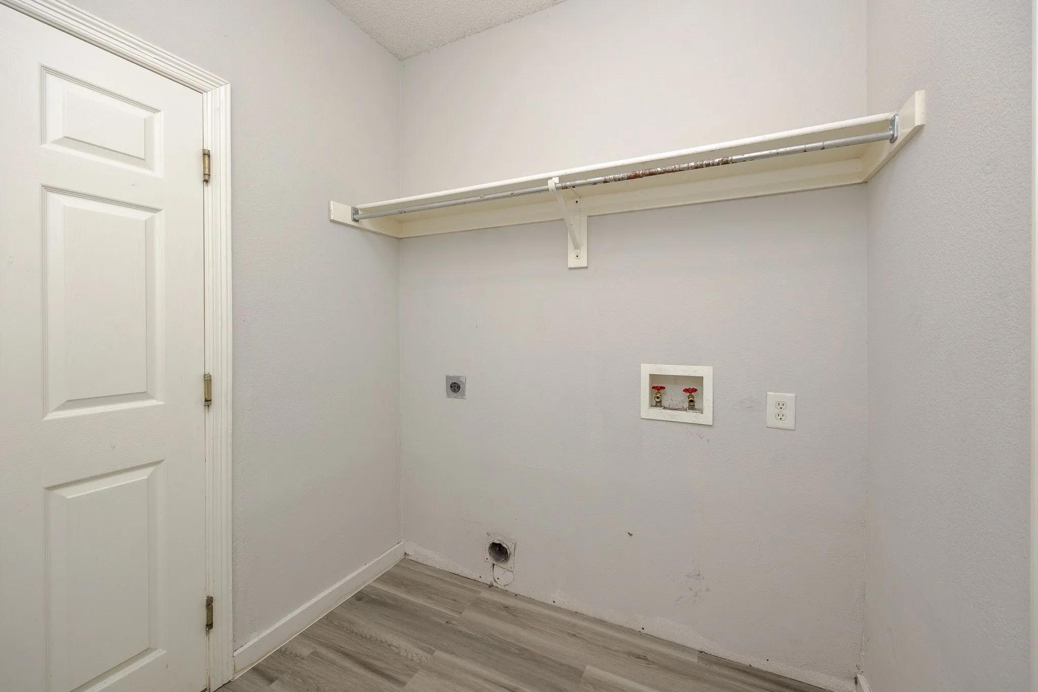 Wood-finish flooring, white paneled door, and built-in shelving