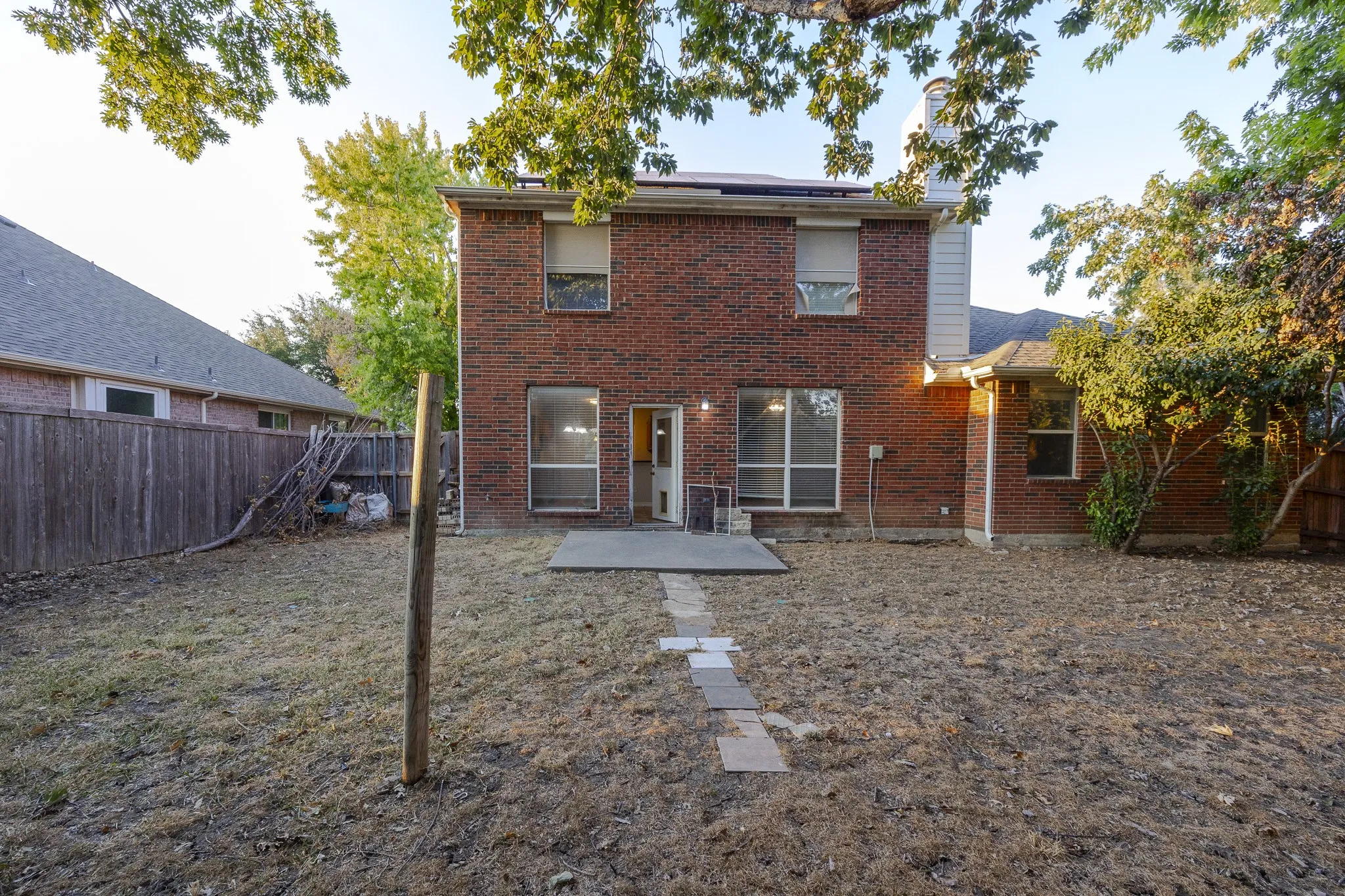 Brick exterior with multiple windows, a concrete patio, and a stone-paver walkway
