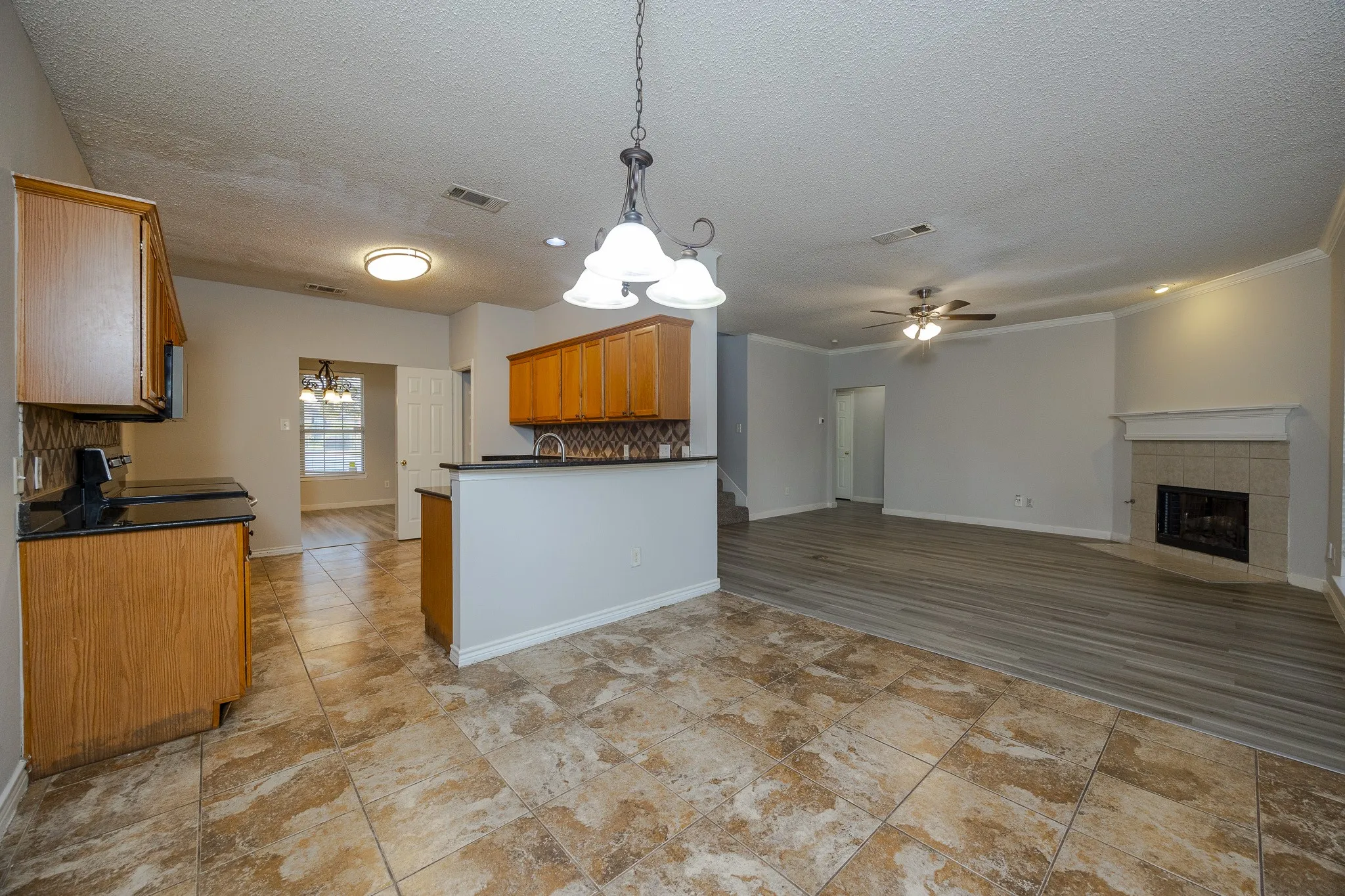 Kitchen with wood cabinetry, black countertops, and a tiled backsplash