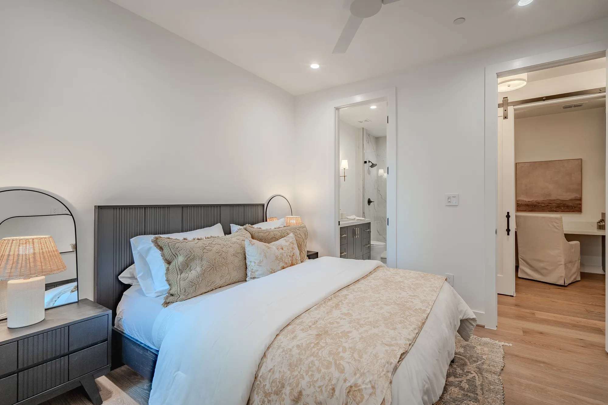 Bedroom featuring a barn door, light wood-type flooring, ensuite bathroom, ceiling fan, and recessed lighting