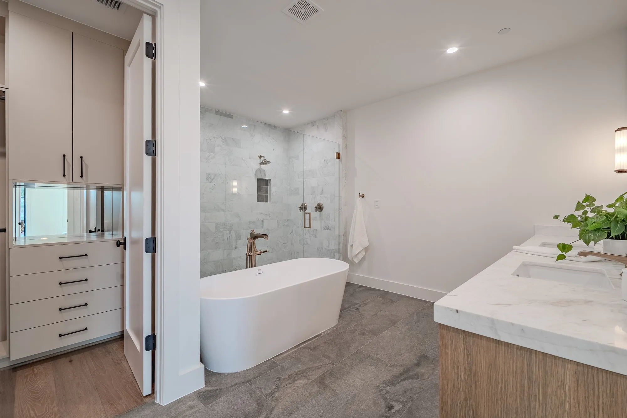 Bathroom featuring a shower stall, a freestanding bath, double vanity, and recessed lighting