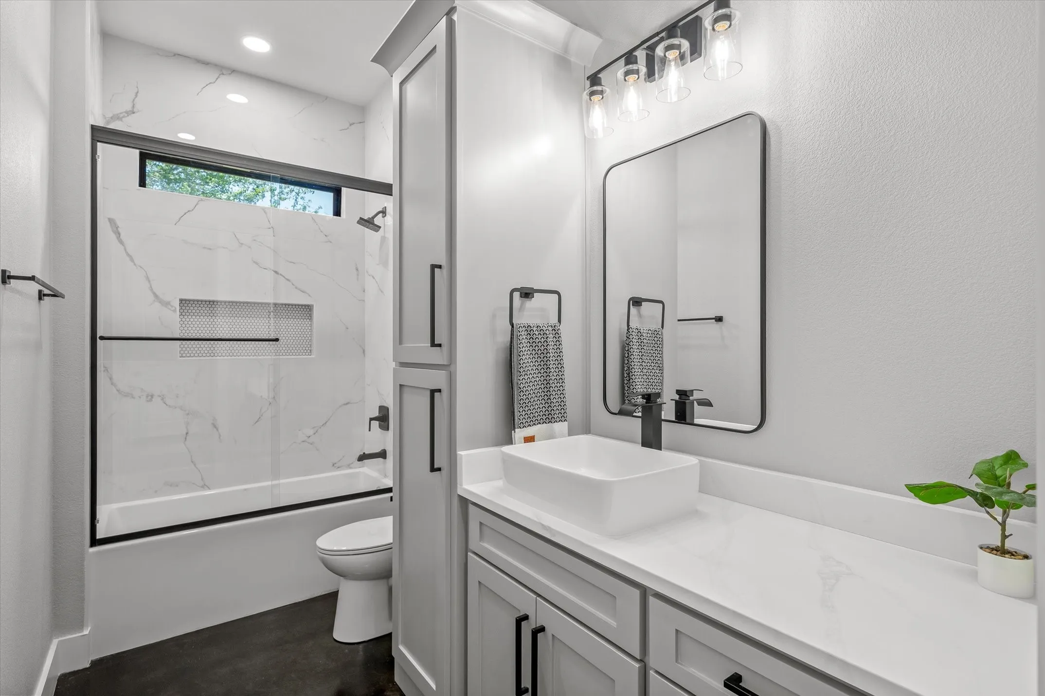 Modern bathroom featuring a rectangular vessel sink, white countertop, and dark-finish hardware