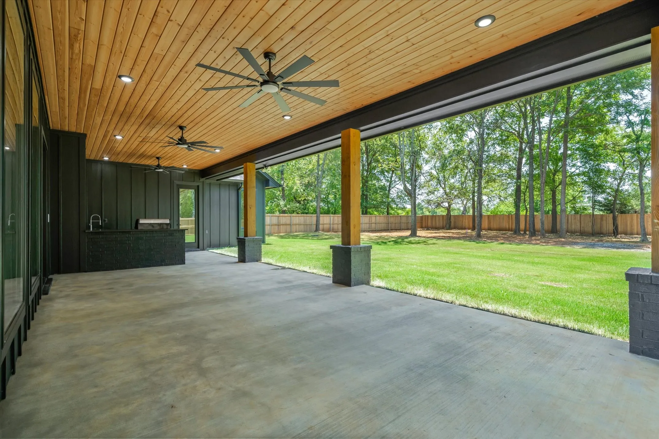 Expansive covered patio featuring a wood-panel ceiling, multiple ceiling fans, and recessed lighting