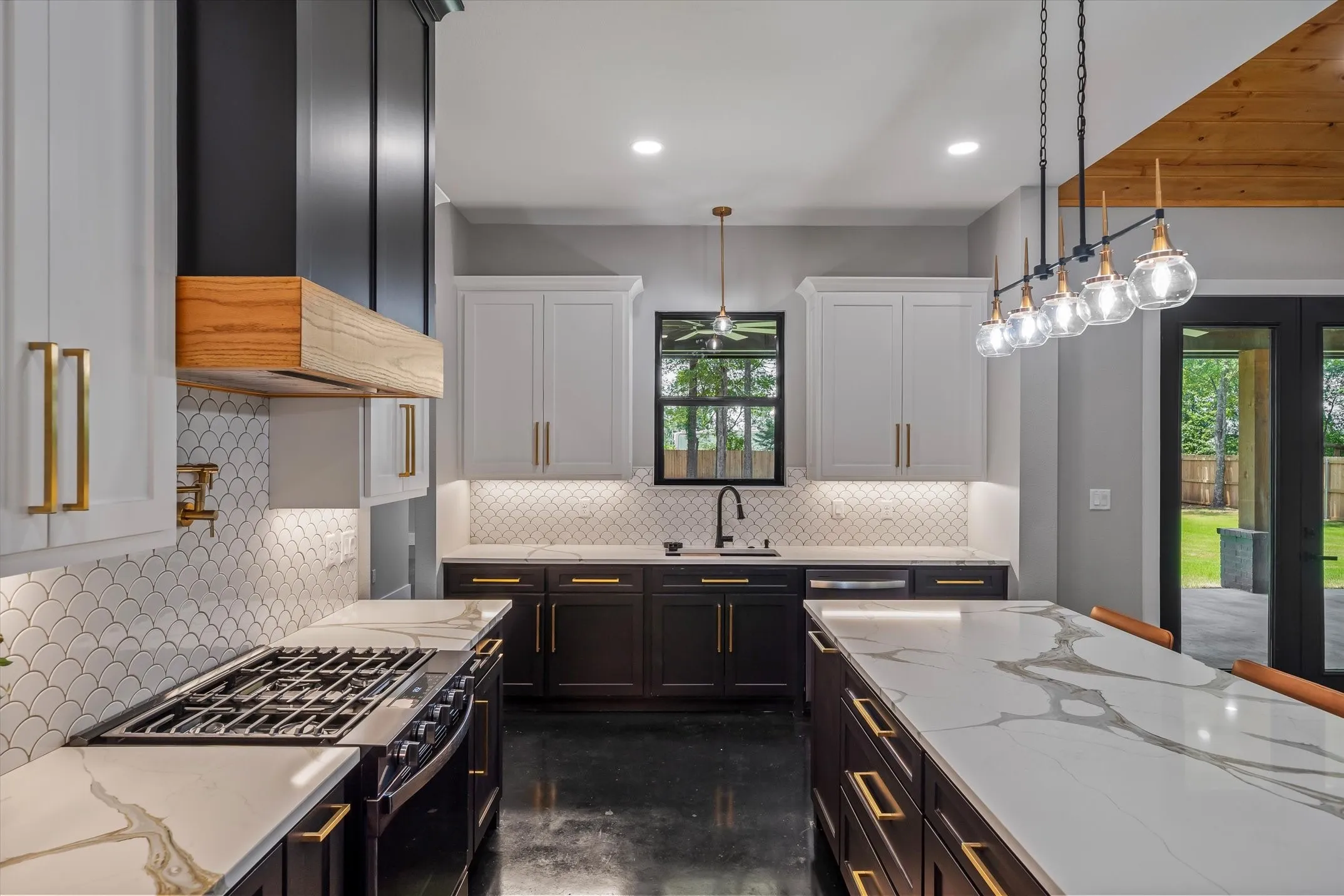 Spacious kitchen featuring a gas range, large center island with seating, dark lower cabinetry, and white upper cabinetry